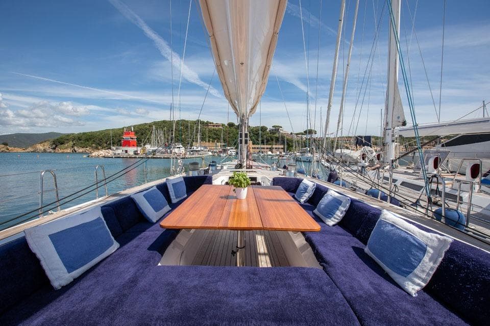 Luxurious 2001 Nautor Swan 80 yacht deck with plush seating and scenic harbor view.
