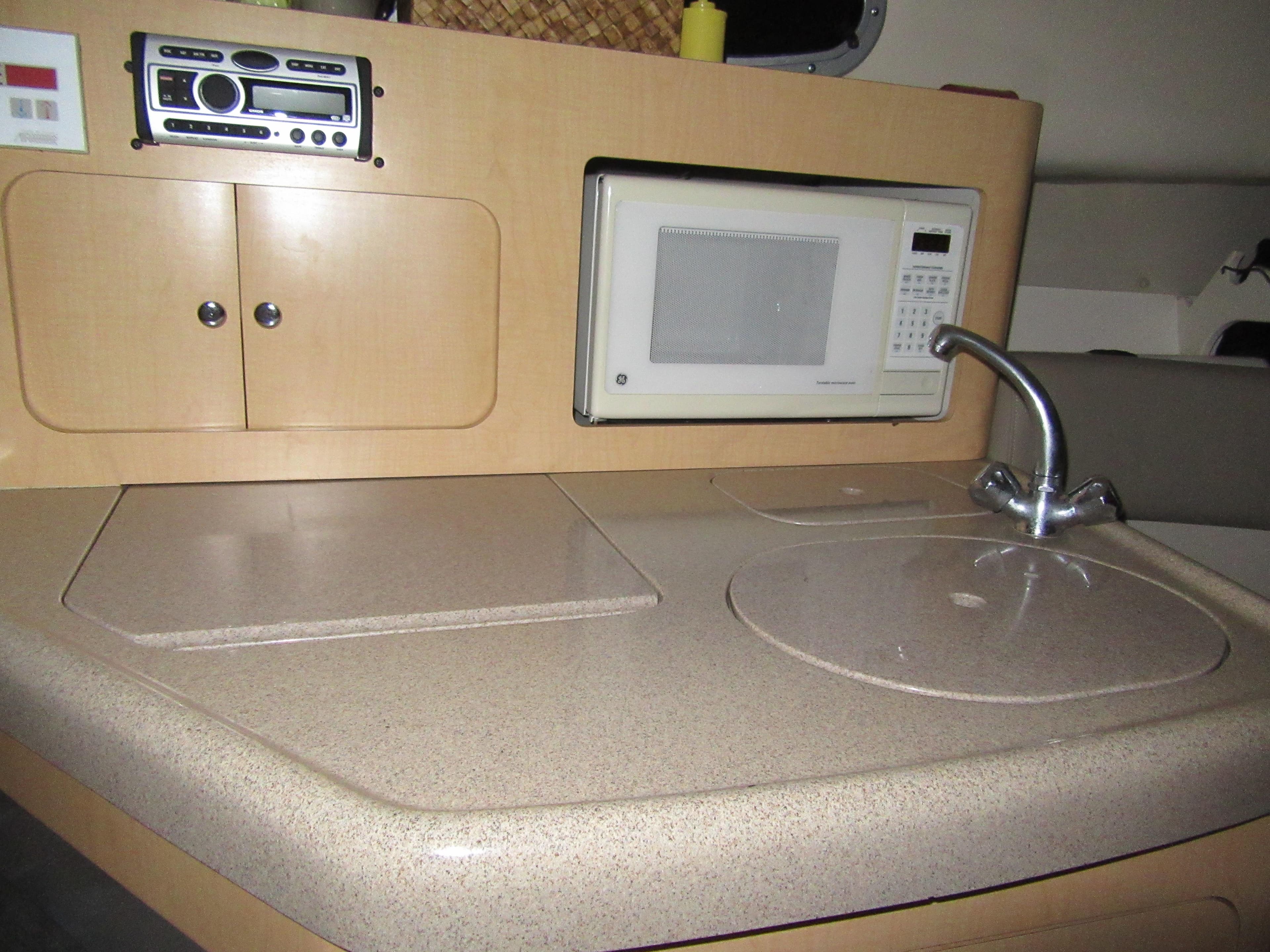 2002 Boston Whaler 295 Conquest galley with microwave, sink, and storage cabinets.