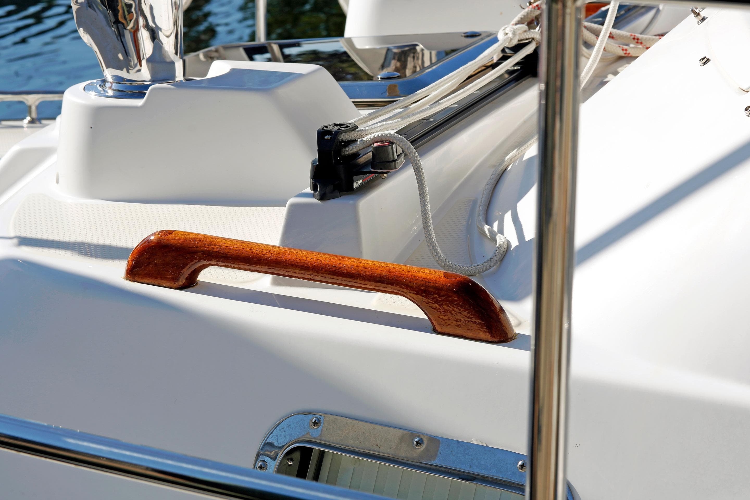 Close-up of a 2012 Hylas 49CC yacht deck with wooden handrail and ropes.