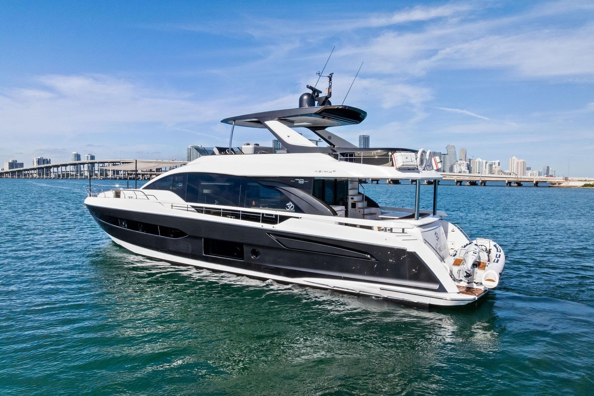 Luxury 2021 Azimut Fly 78 yacht cruising near city skyline on a sunny day.