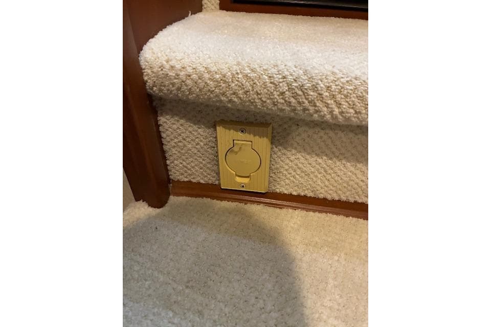 Carpeted stairs with a wooden outlet cover on a 2004 Silverton 48 Convertible.