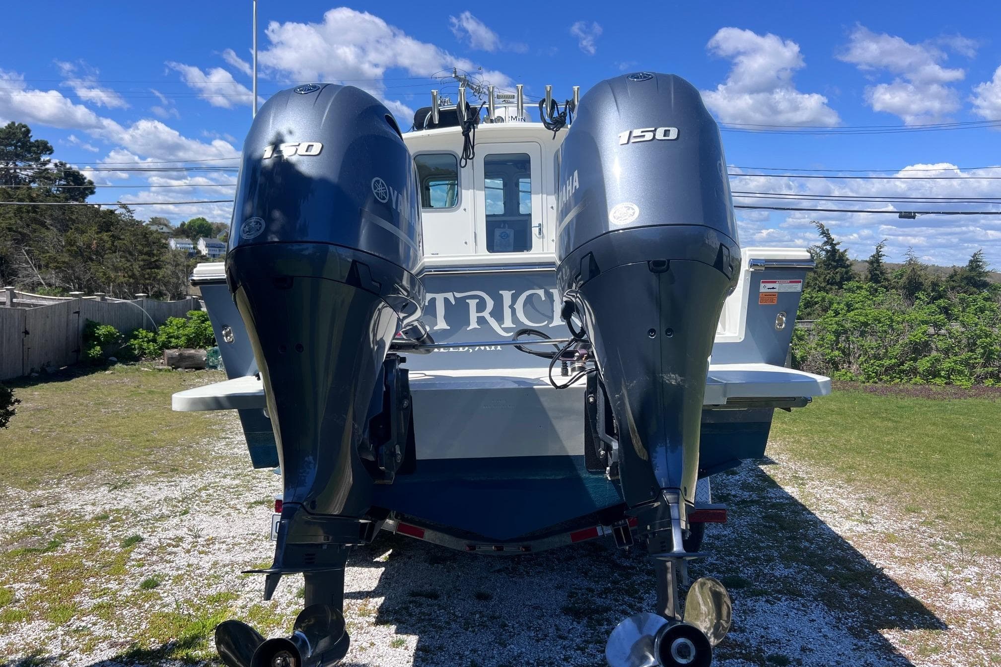 2023 Parker 2520 XLD Sport Cabin boat with dual Yamaha 150 engines, parked outdoors.