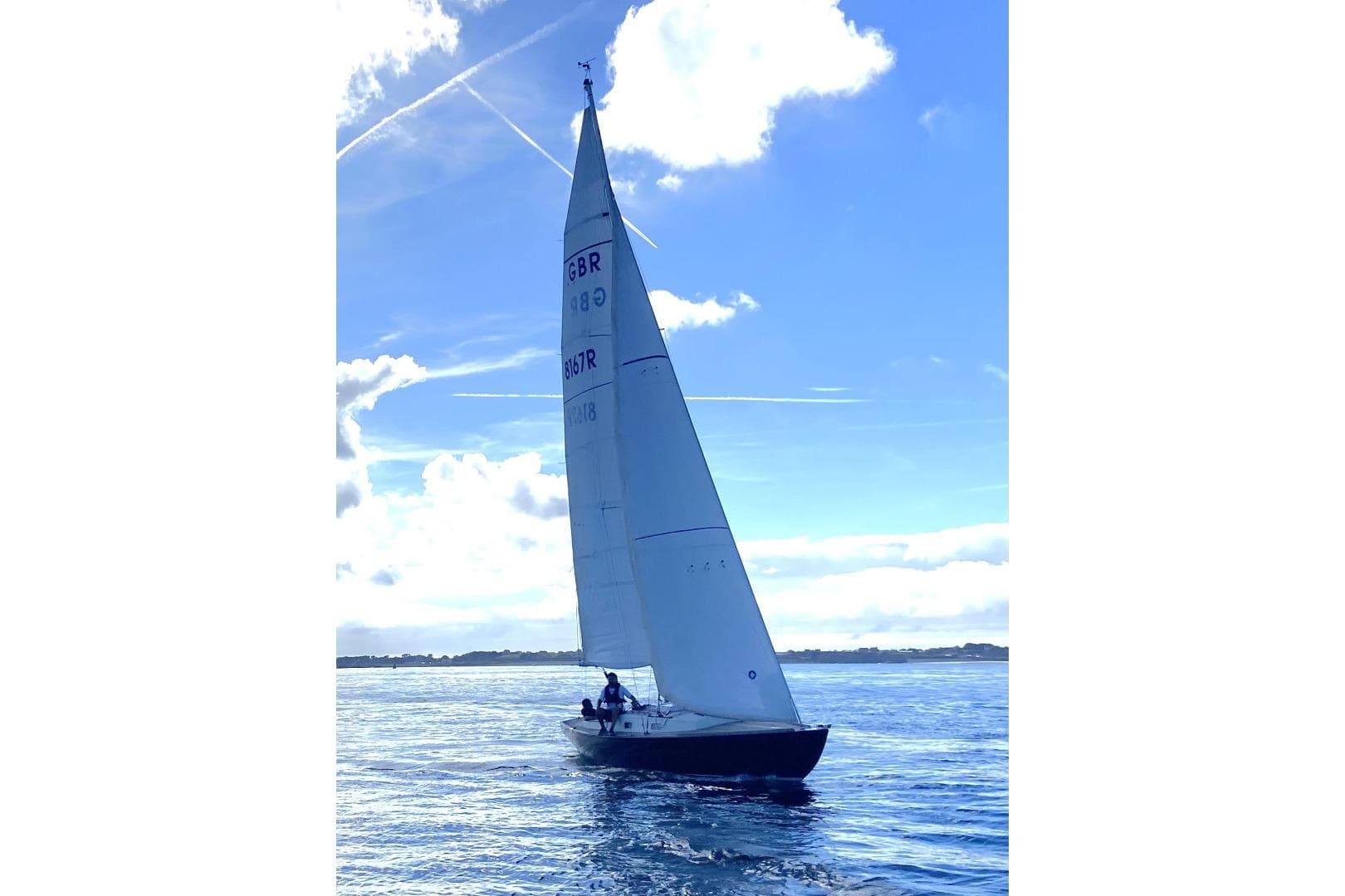 Sailing yacht Rustler 33, 2013 model, gliding on calm blue waters under a clear sky.