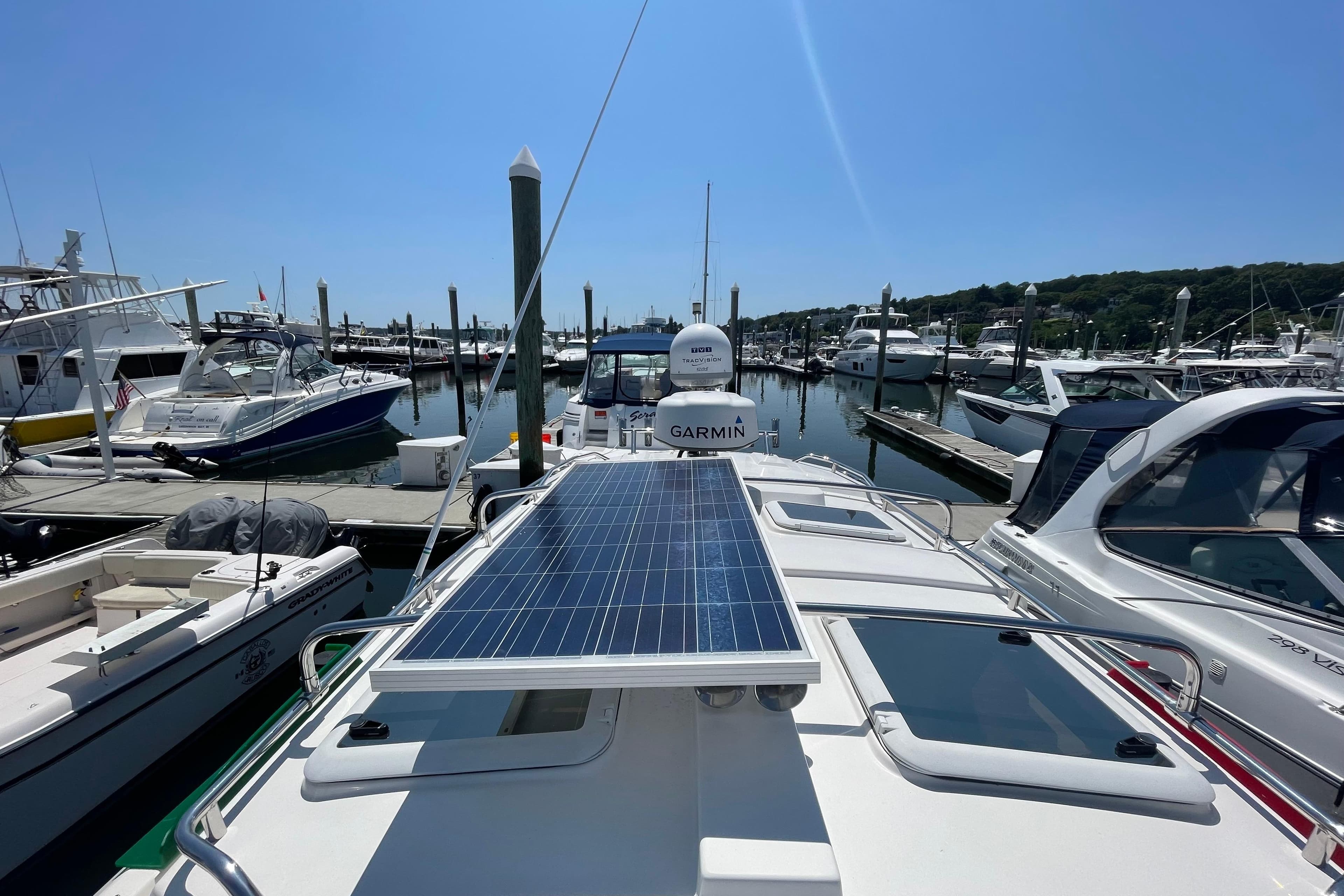 2019 Cutwater C-28 boat with solar panel, docked in a marina under clear blue sky.