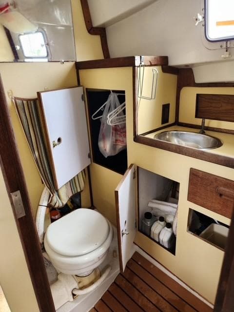 1977 Bombay Express boat bathroom with toilet, sink, and storage cabinets.