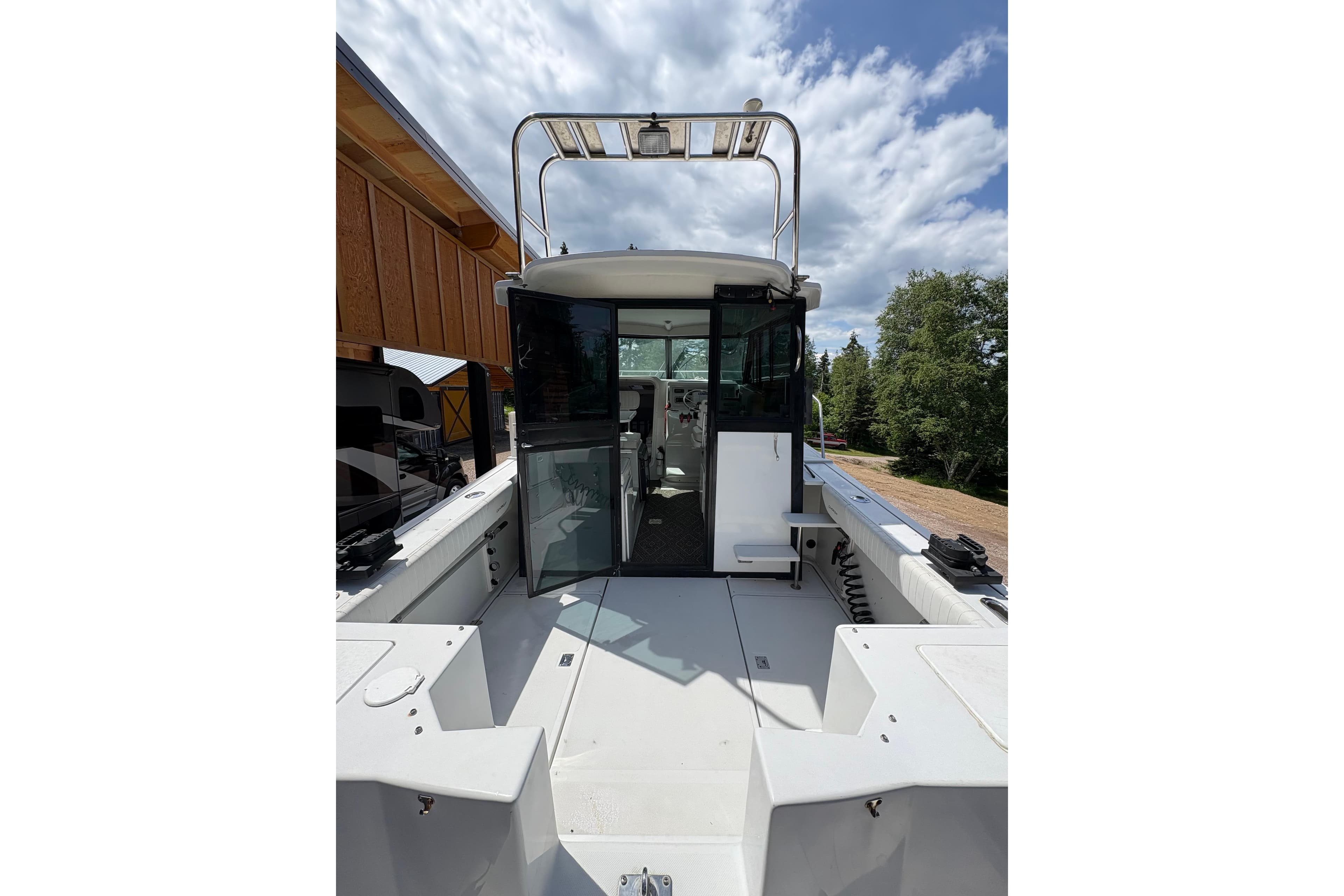 2001 Glacier Bay 2690 Coastal Runner boat with open cabin, docked under a partly cloudy sky.