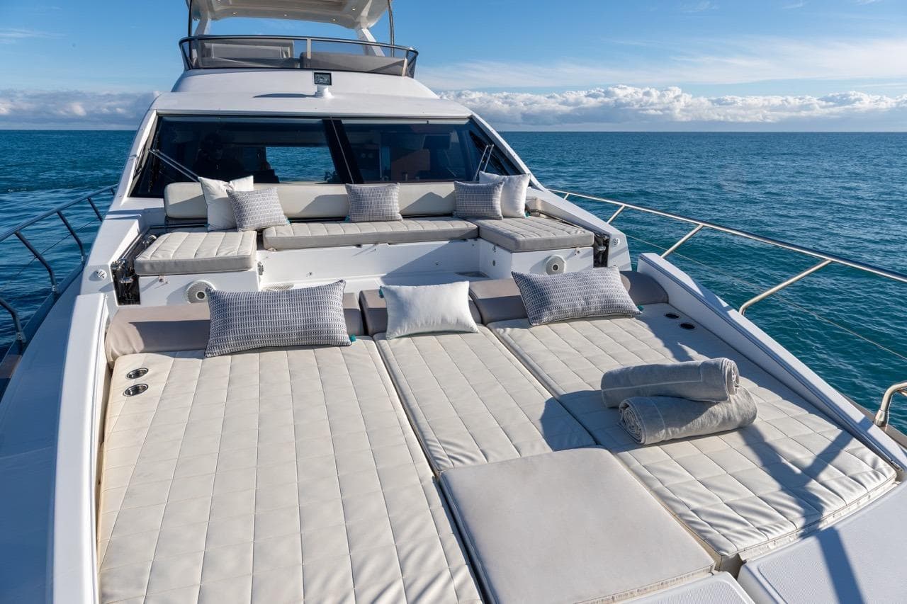 Luxurious 2016 Azimut 66 yacht with sunbathing deck, cushions, and ocean view.