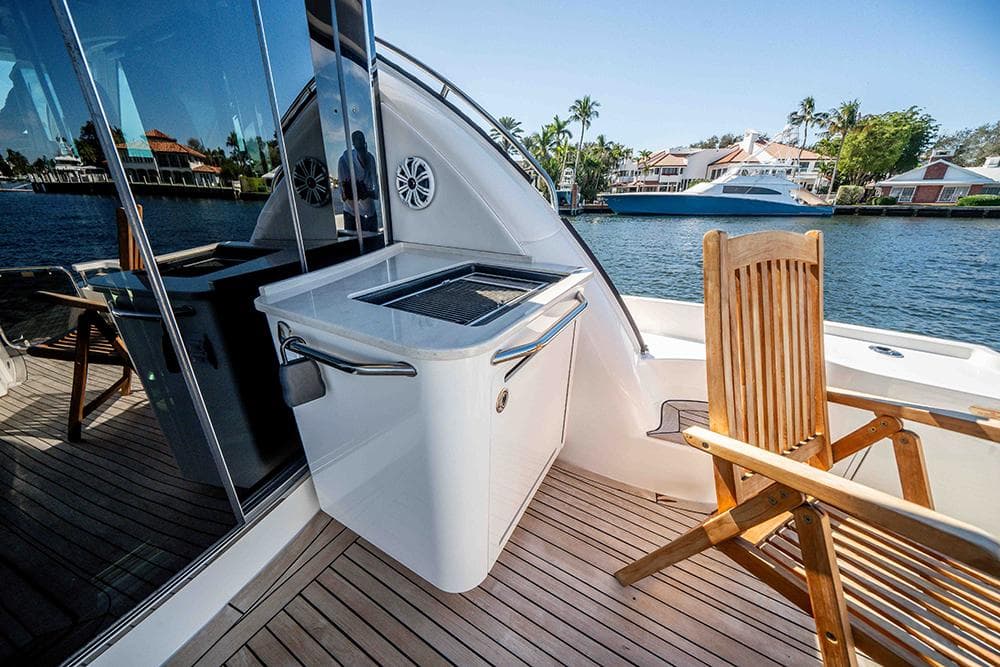 2012 Sea Ray 610 Sundancer yacht deck with grill and wooden chair by waterfront homes.
