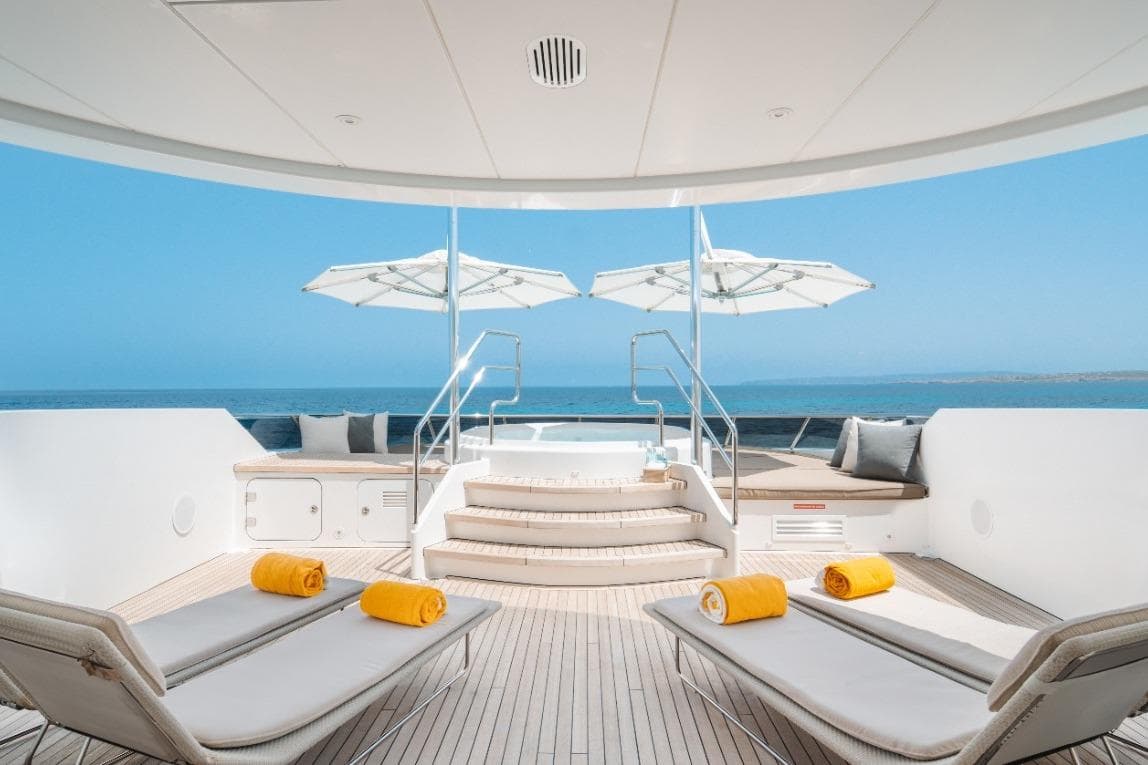 Luxurious Heesen 47 yacht deck with sun loungers, umbrellas, and ocean view, 2015 model.