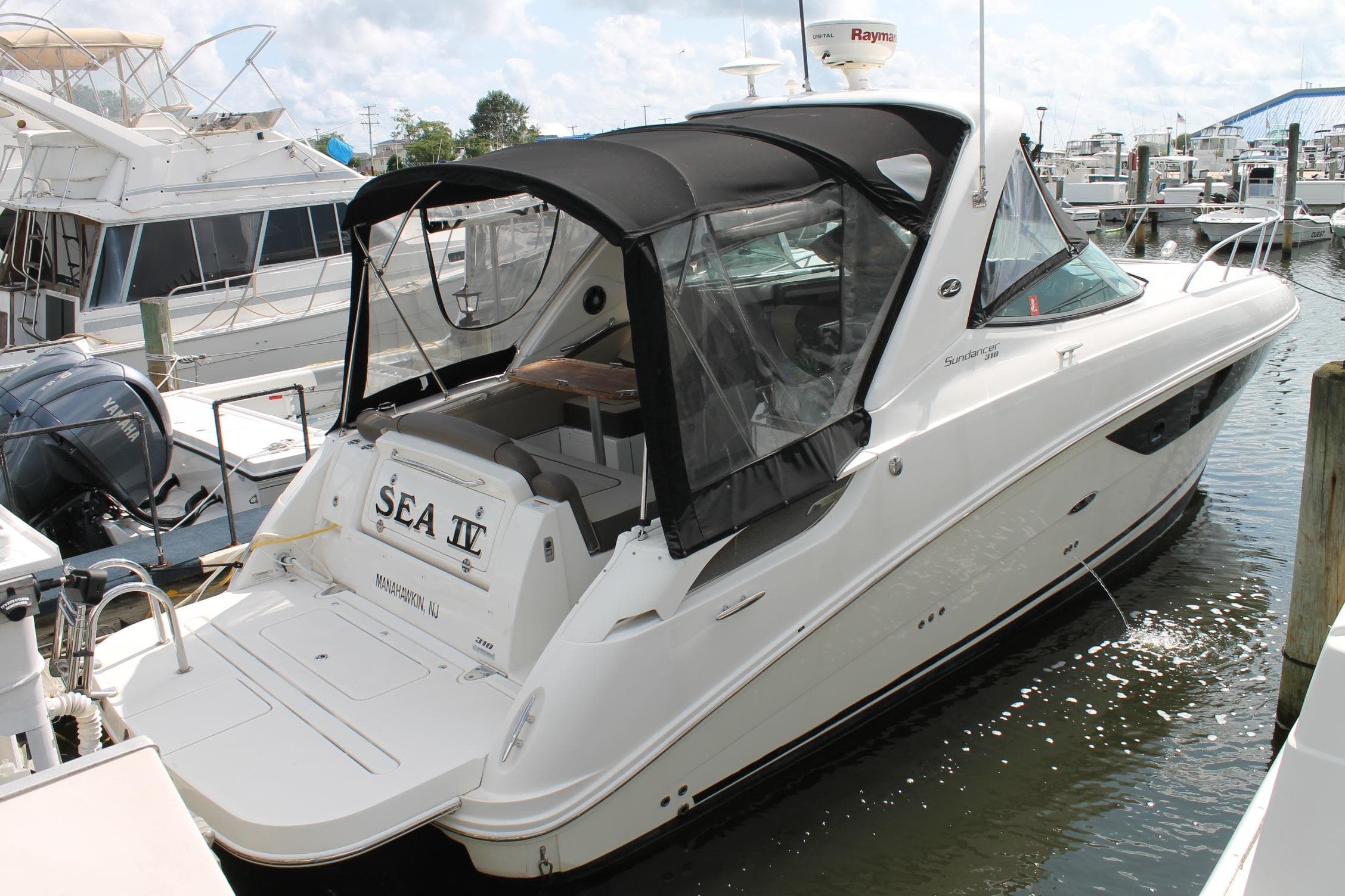 2015 Sea Ray Sundancer 310 docked at marina, featuring sleek design and black canopy.