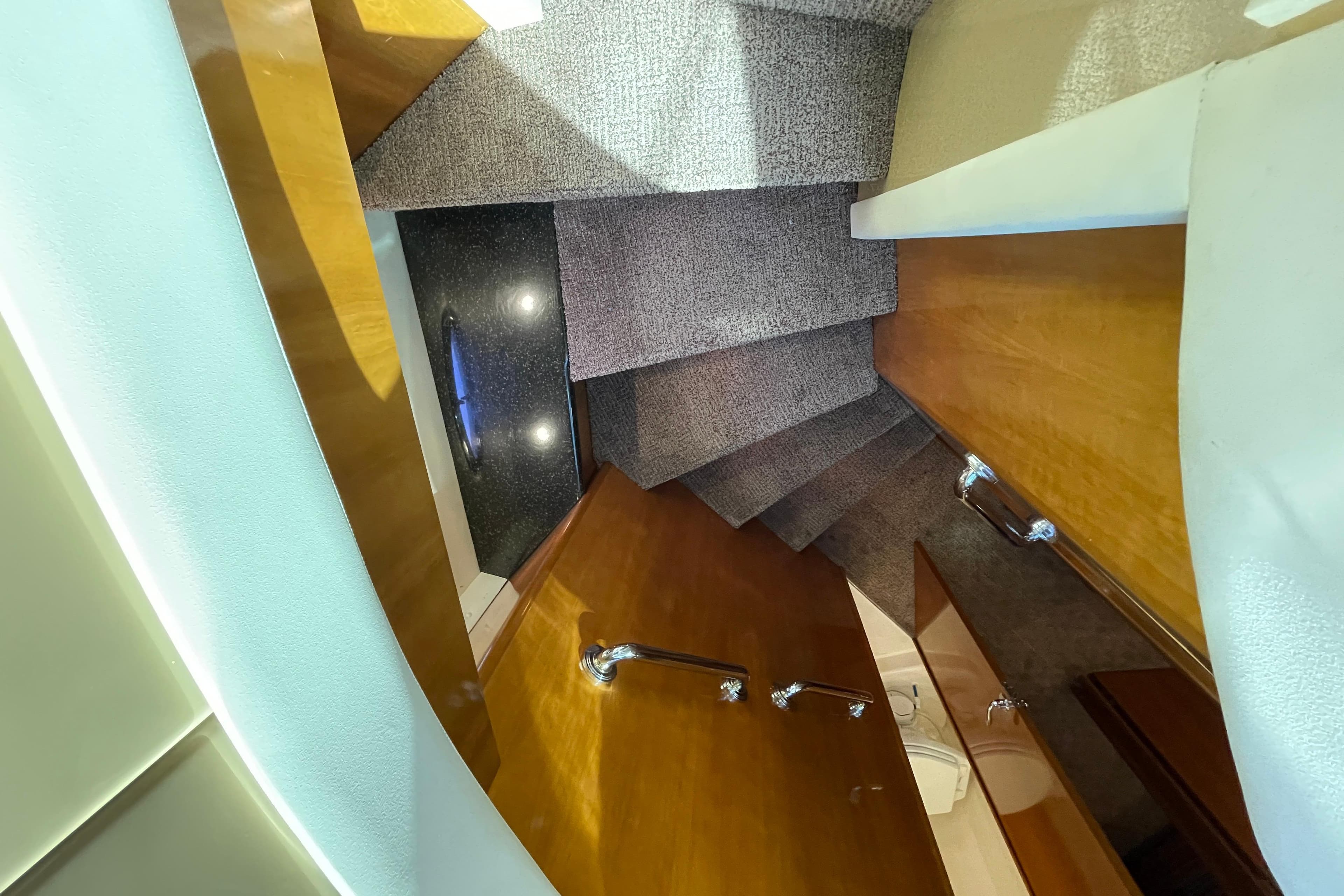 Staircase inside 2002 Carver 570 Voyager Pilothouse with carpeted steps and wooden handrails.