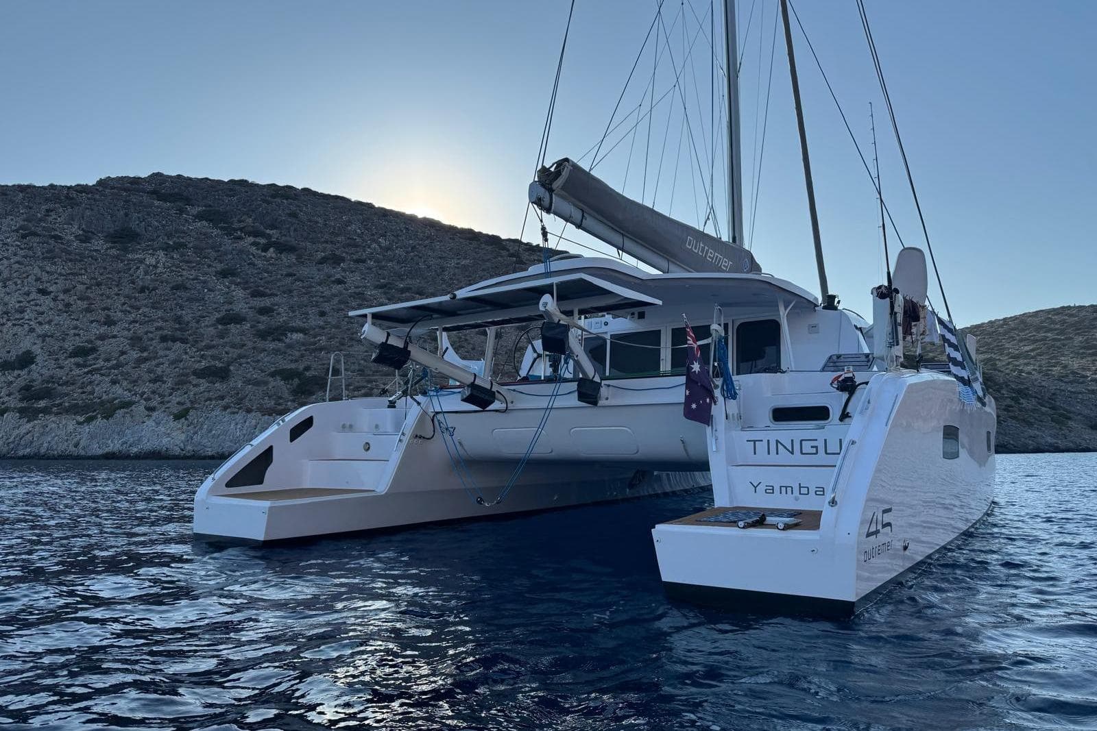 2024 Outremer 45 catamaran anchored in serene waters near rocky coastline.