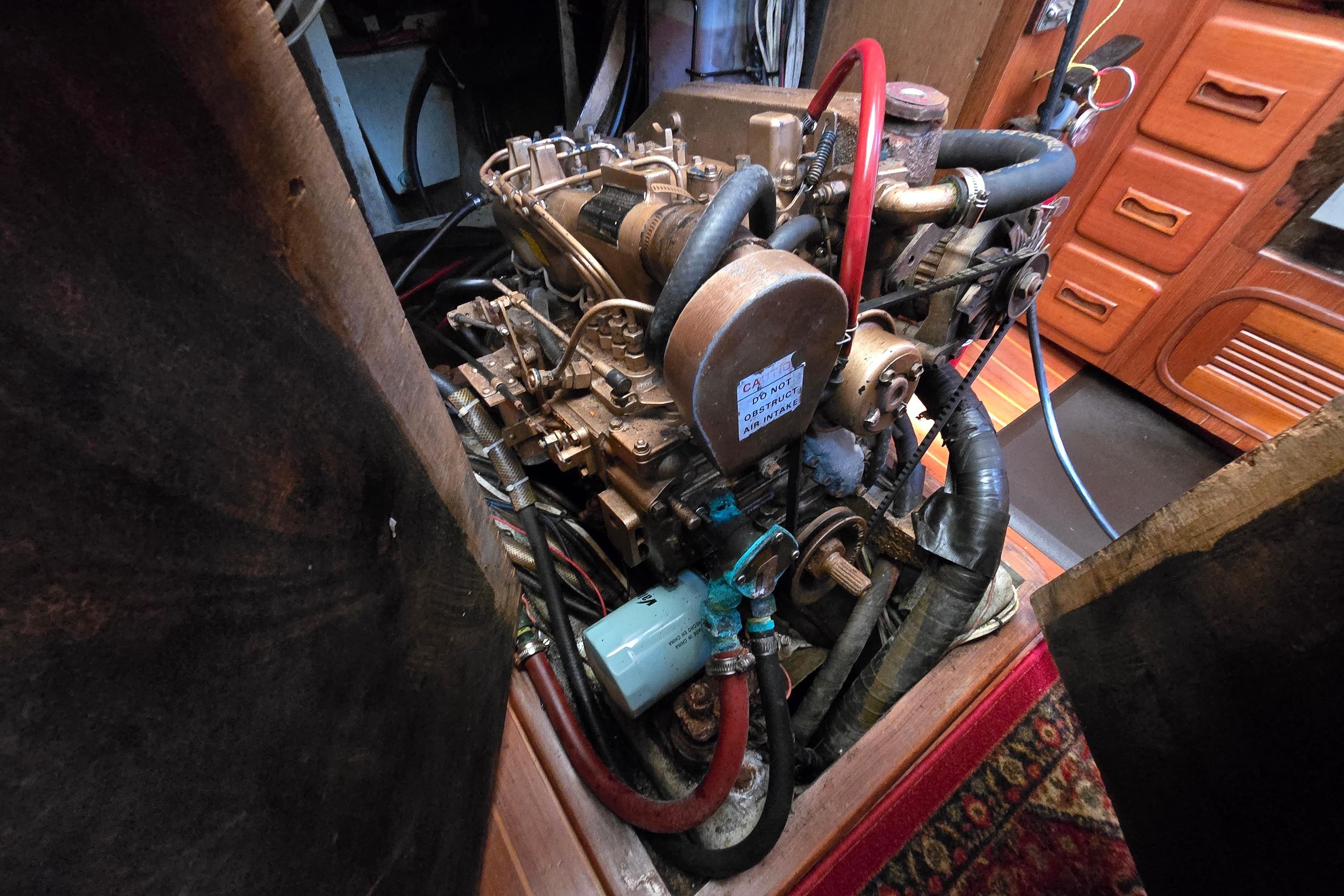 Engine compartment of a 1985 Baba 35 sailboat, showcasing mechanical components and hoses.
