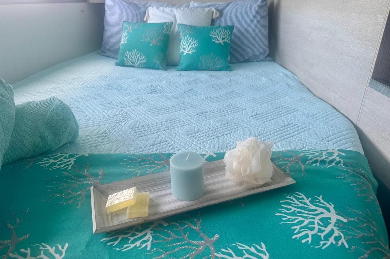 Cozy bedroom in Leopard 45 yacht, featuring teal decor and a relaxing candle setup.