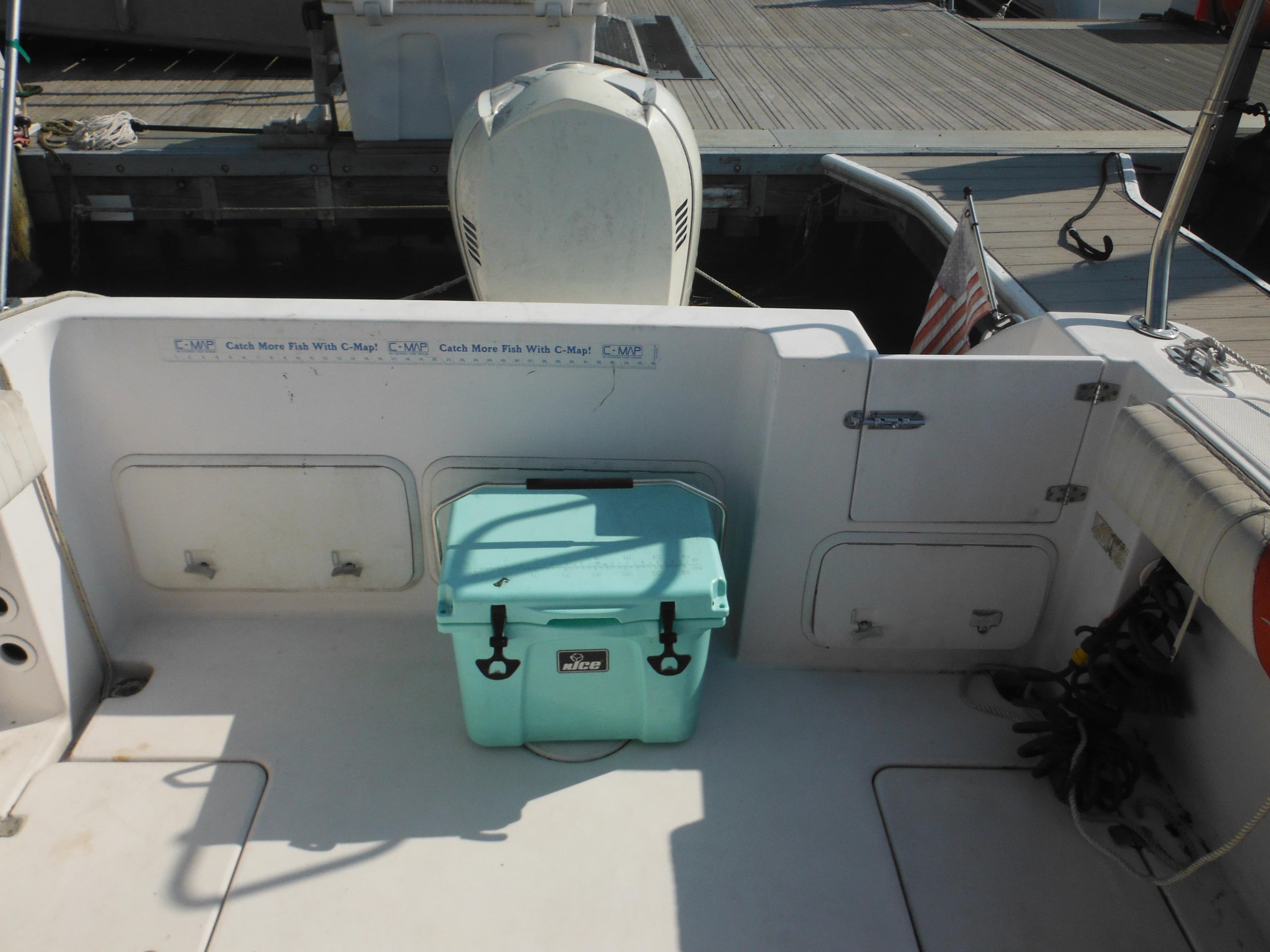 2002 Pro-Line 23 Walk boat deck with cooler and outboard motor.