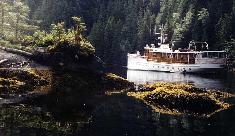 1929 Custom HOFFAR-BEECHING Fantail Yacht in a serene forested cove.