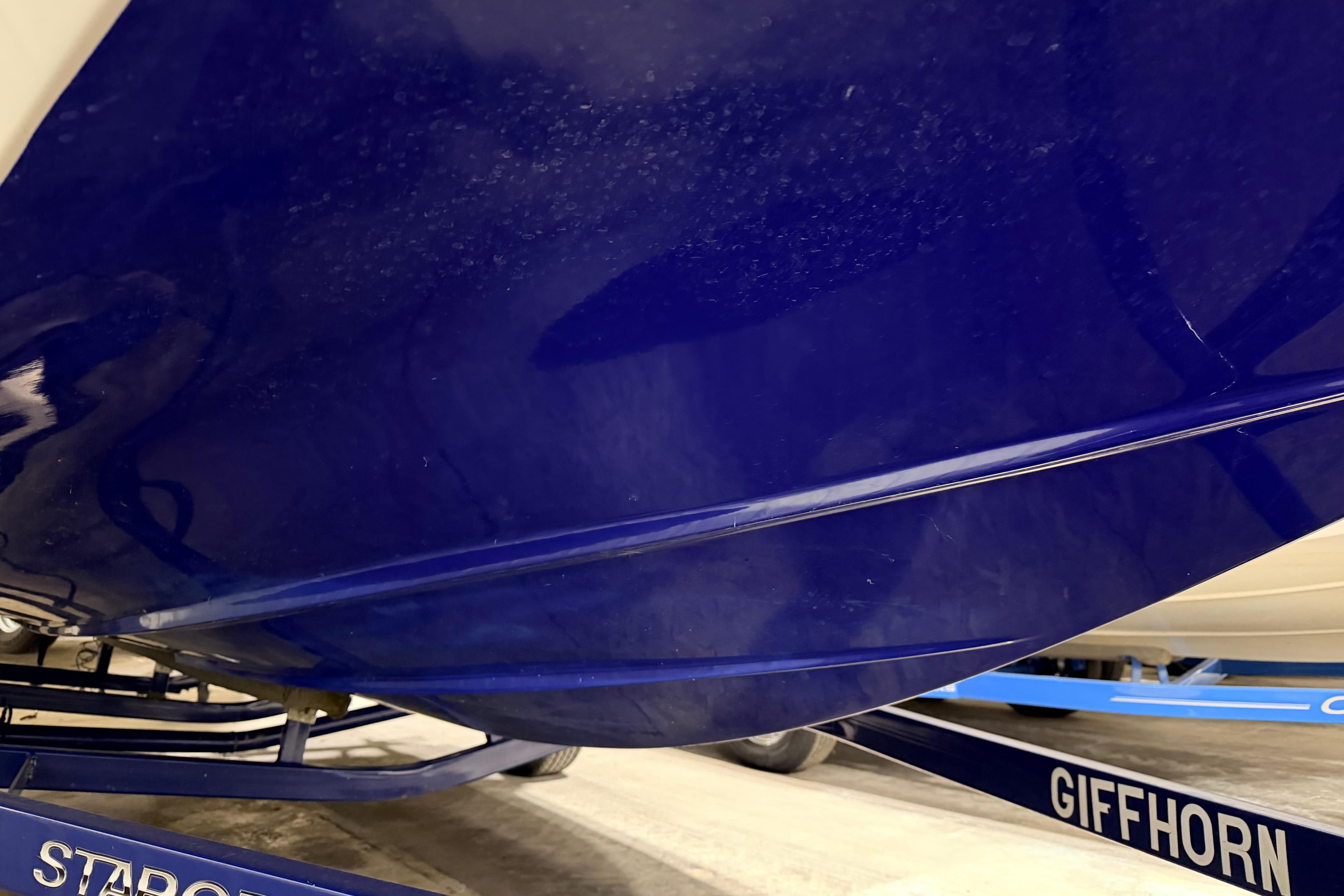 Blue hull of a 2014 Starcraft 2000 IO Limited boat on a trailer.