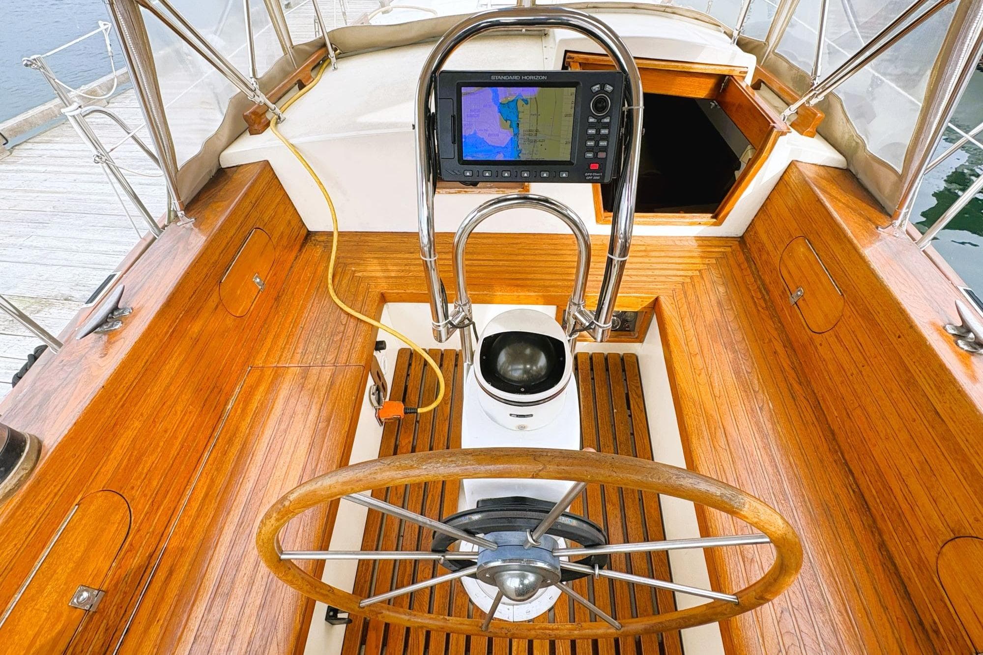 Wooden cockpit of 1980 Discovery 42 sailboat with steering wheel and navigation system.