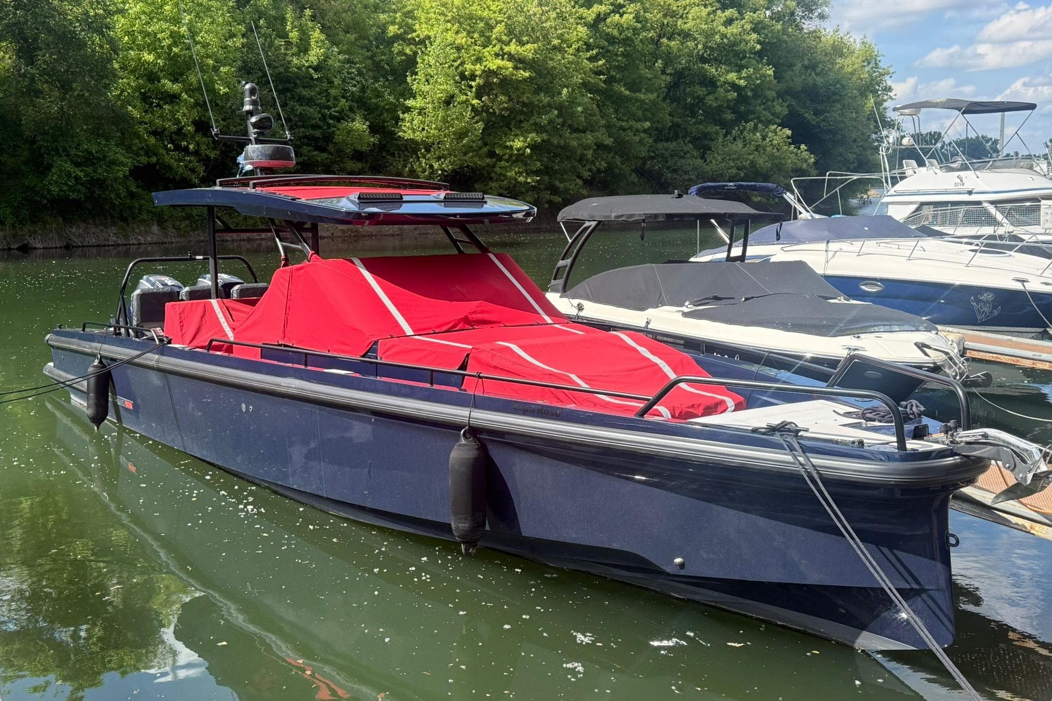 2022 Axopar Brabus Shadow 900 Sun-Top boat with red cover docked on a sunny day.