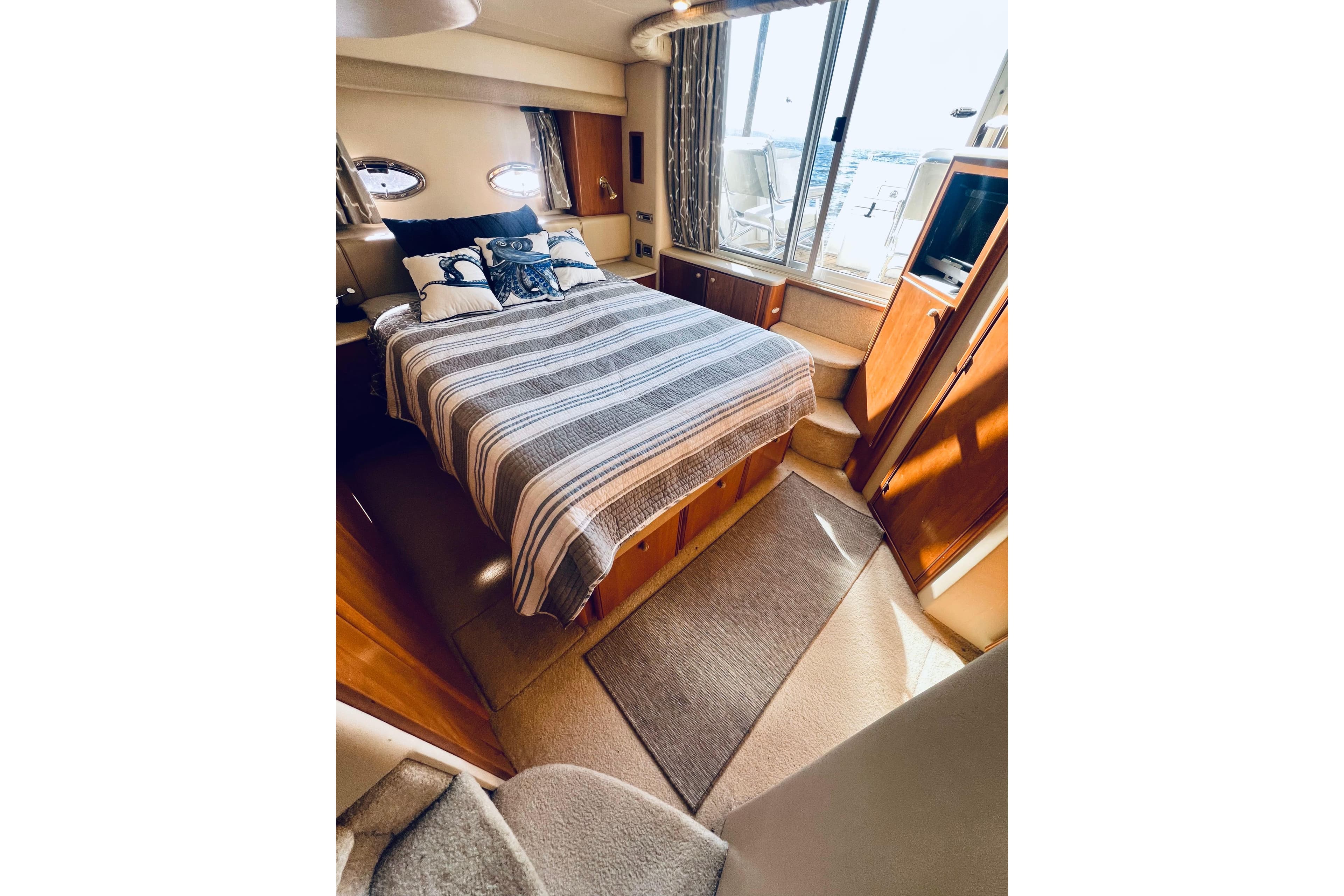 Luxurious 2004 Meridian 459 Motoryacht bedroom with striped bedding and scenic window view.