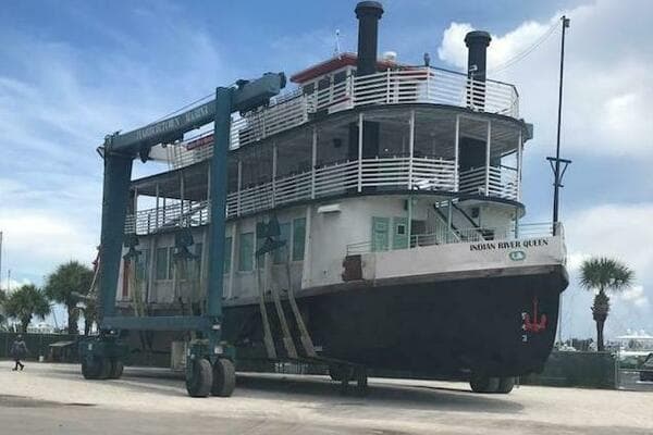 A 1984 custom paddle wheel boat, "Indian River Queen," on a lift at a marina.