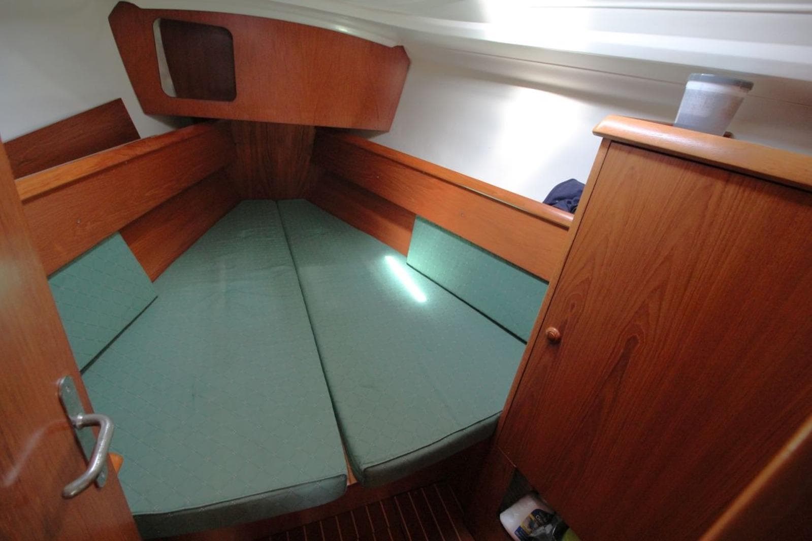 Cozy cabin interior of 2004 Jeanneau Sun Odyssey 35 sailboat with green cushions.