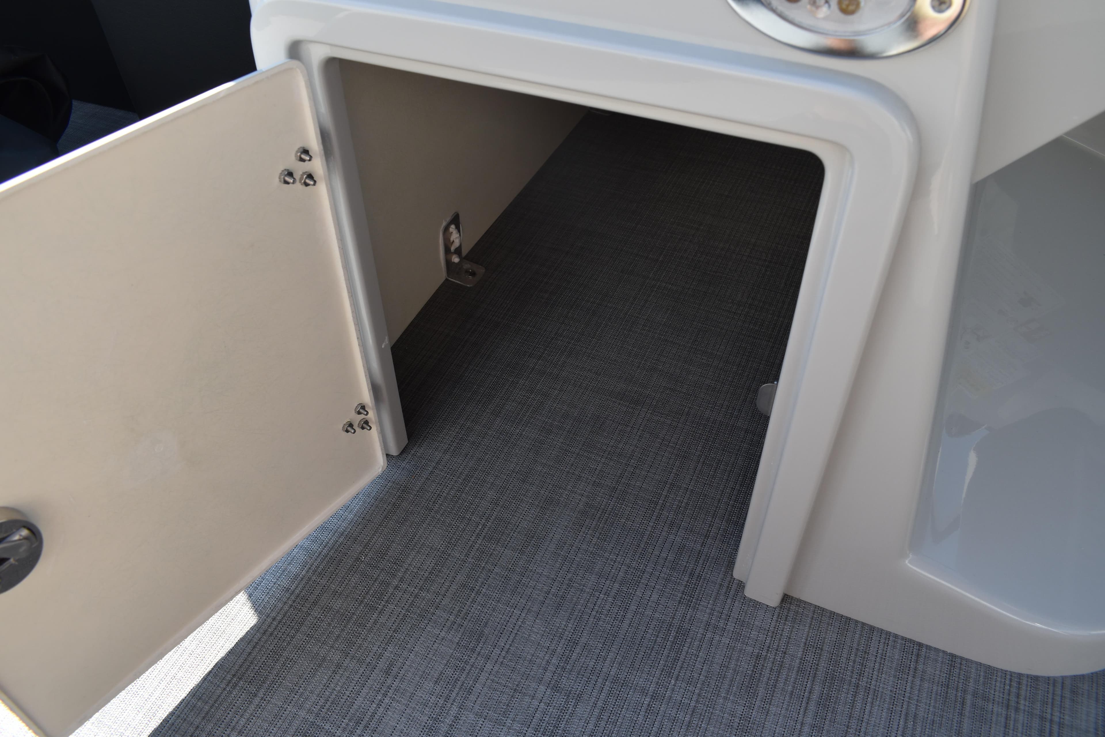 Open storage compartment on 2026 Lowe SF 232 Sport Fish boat, featuring gray flooring.