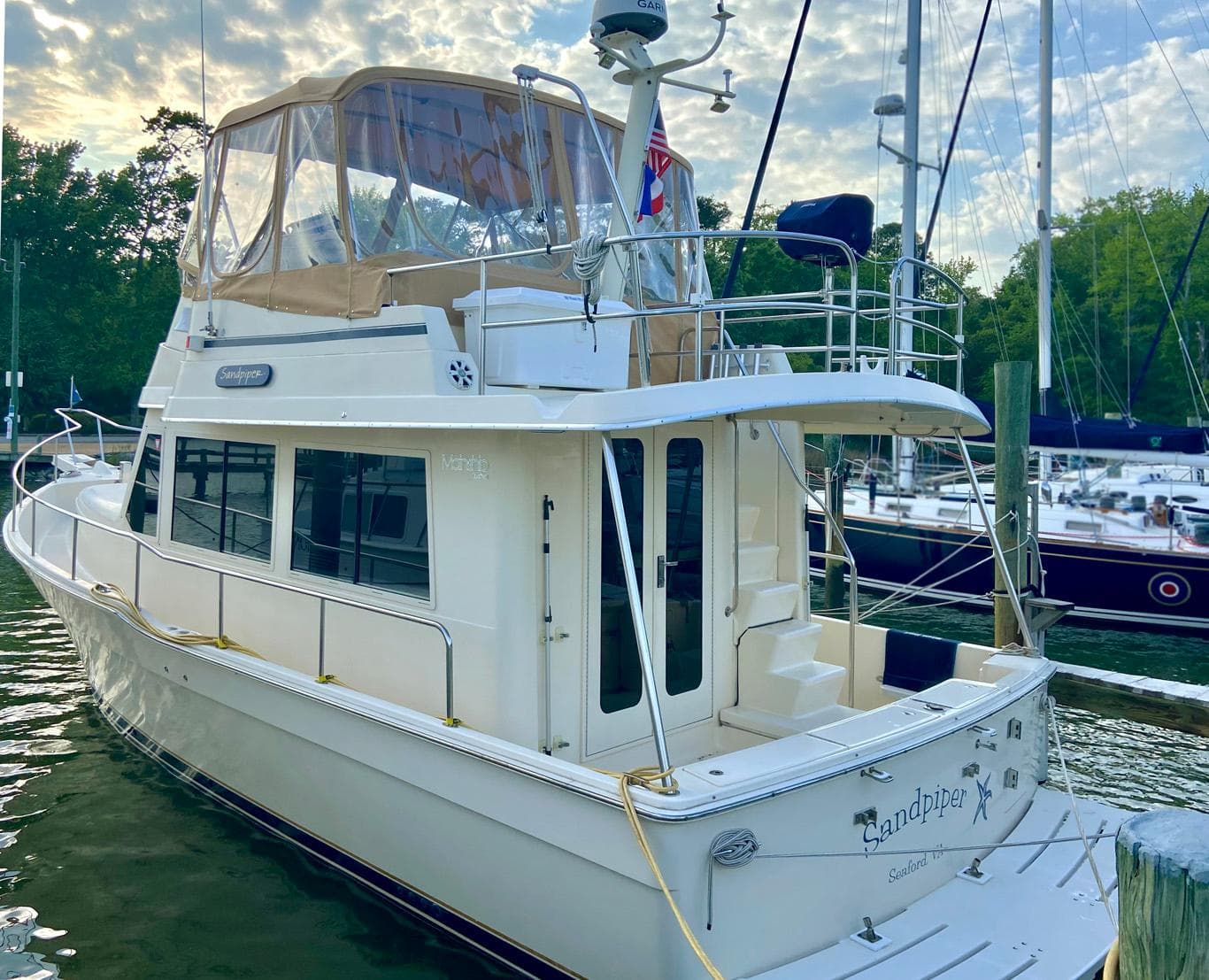 2004 Mainship 340 yacht docked at marina, featuring upper deck and enclosed cabin.