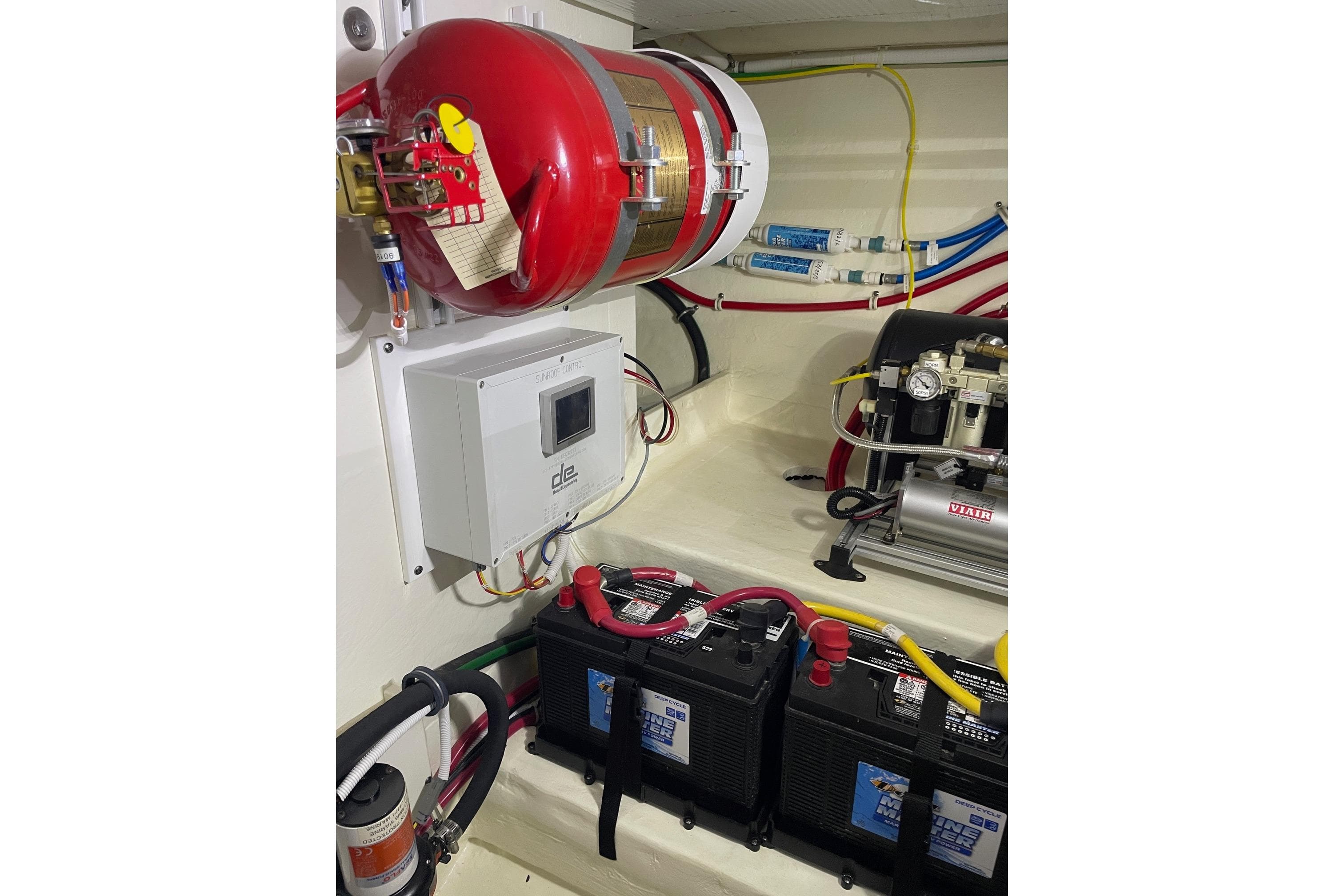 Engine room of 2023 Tiara Yachts C44 Coupe with fire extinguisher and battery setup.