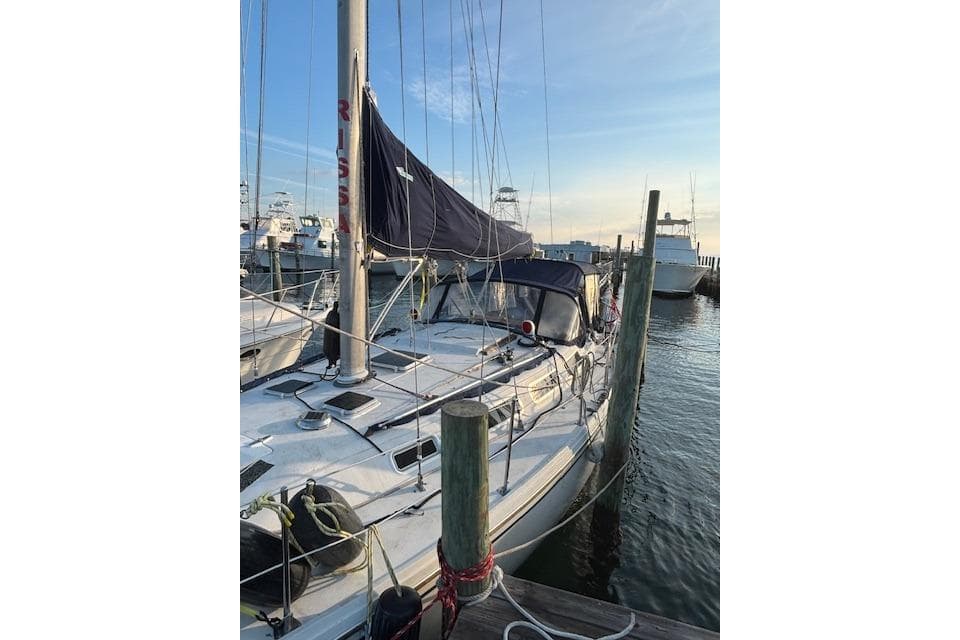 1986 Catalina 36 sailboat docked at marina, with blue sky and calm water.