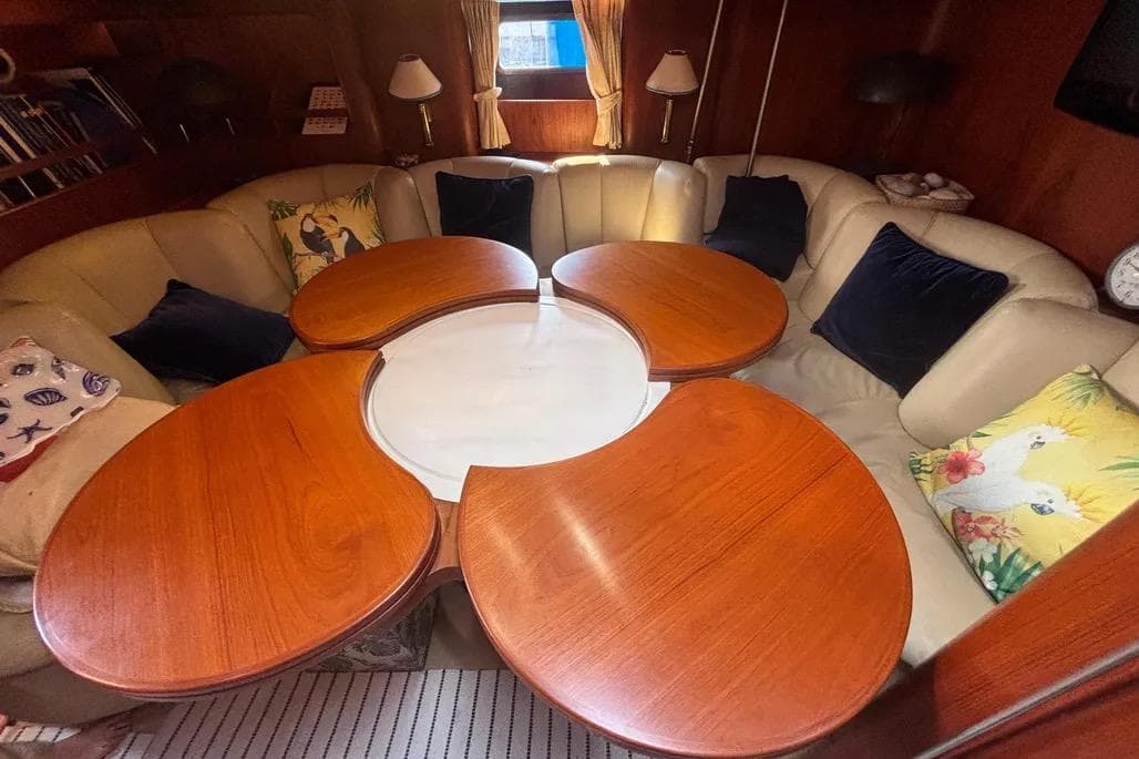 Luxurious 1988 Jongert yacht interior with circular wooden table and plush seating.