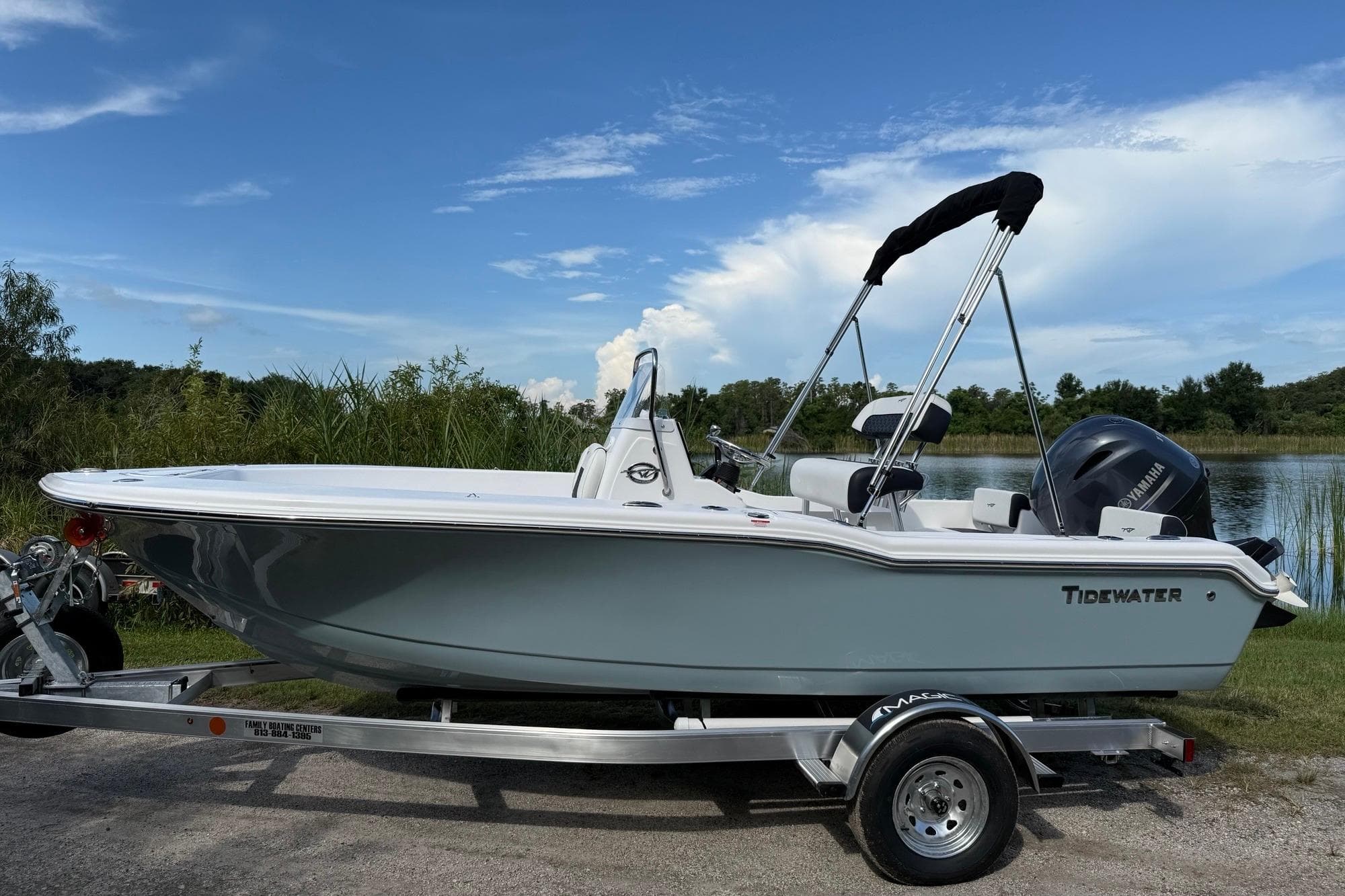 2026 Tidewater 180 CC Adventure boat on trailer by a lake under blue sky.