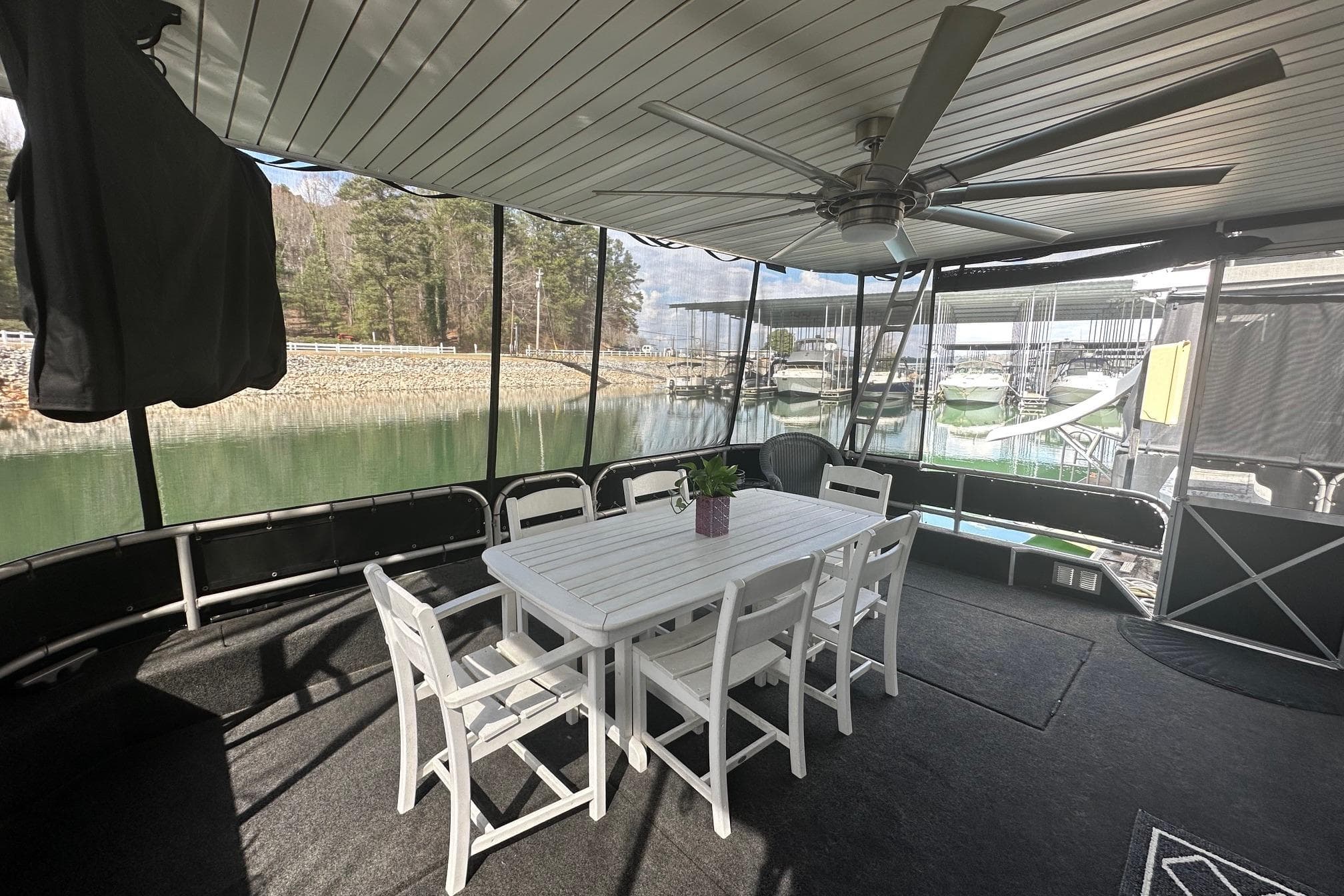 Outdoor dining area on 2004 Sumerset 16x82 houseboat with lake view and ceiling fan.