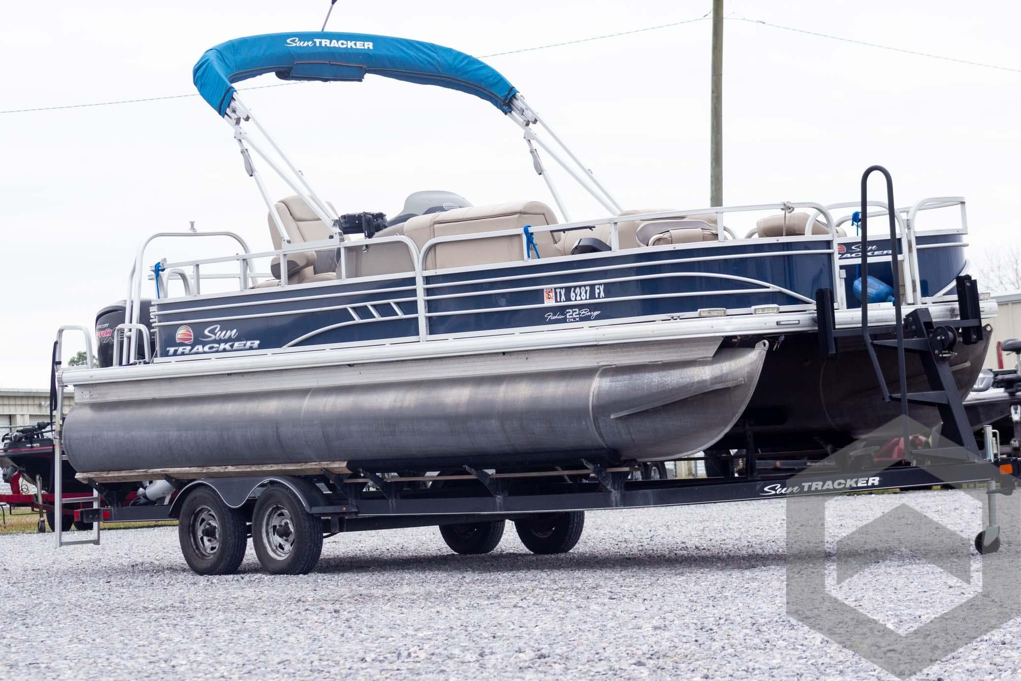 2020 Sun Tracker Fishin' Barge 22 DLX pontoon boat on trailer, blue canopy.