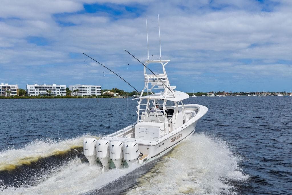 2018 Regulator 41 boat cruising on water with four engines, coastal buildings in background.