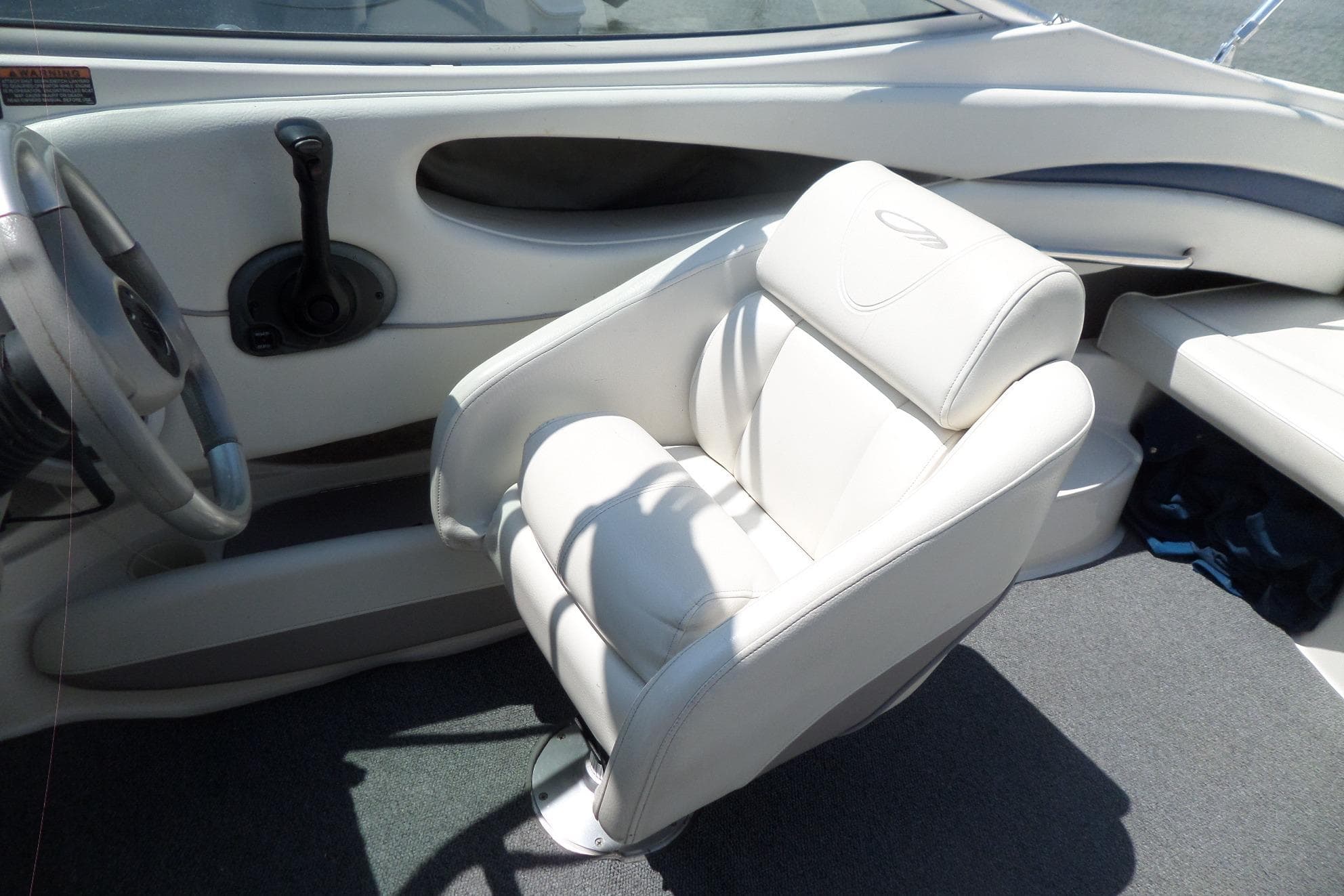 Interior of 2003 Maxum 2400 SC boat featuring a white captain's chair and steering wheel.