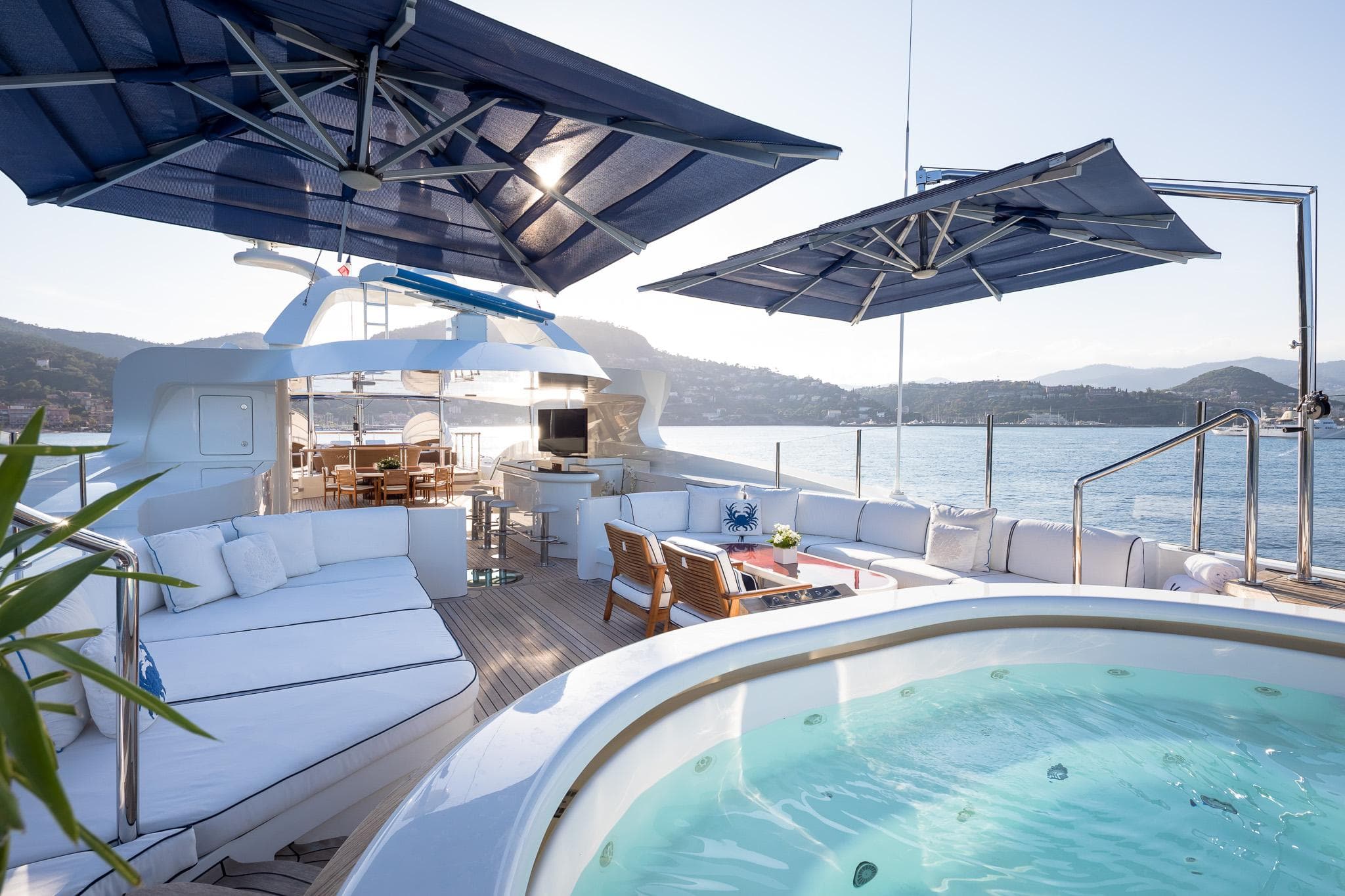 Luxurious 2011 Benetti 60 yacht deck with jacuzzi, seating, and umbrellas overlooking serene waters.