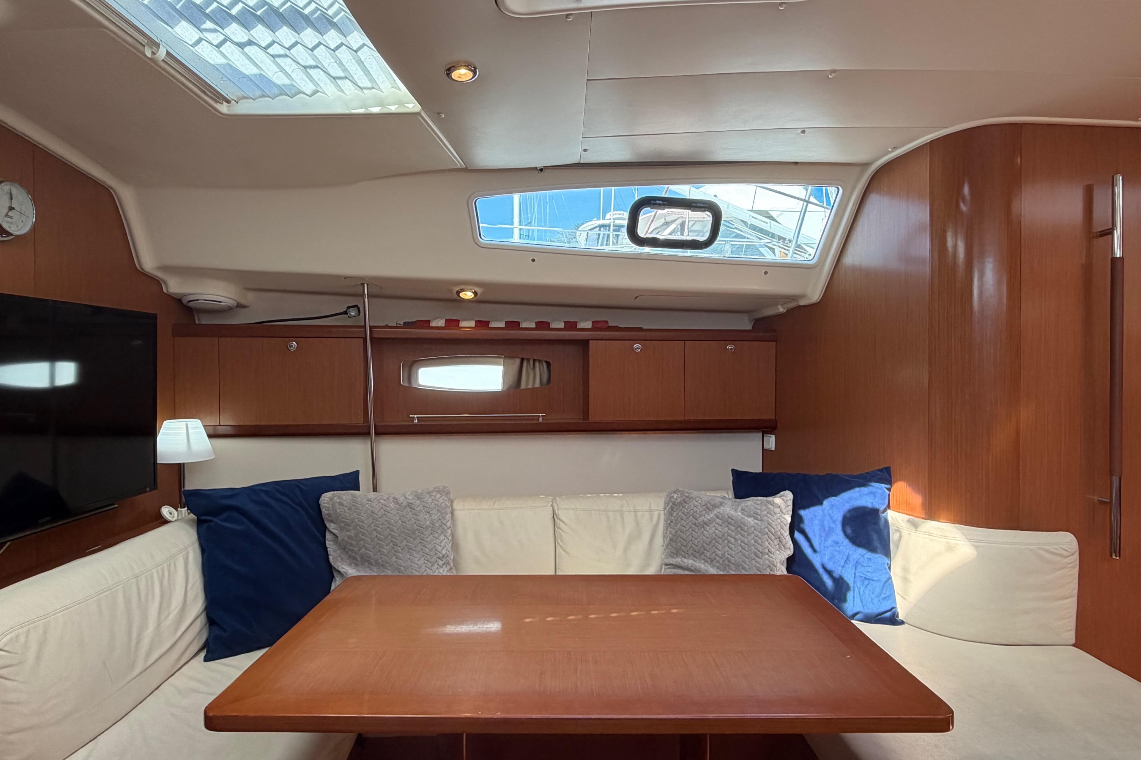 Interior of 2008 Beneteau 43 yacht with cozy seating and wooden finishes.