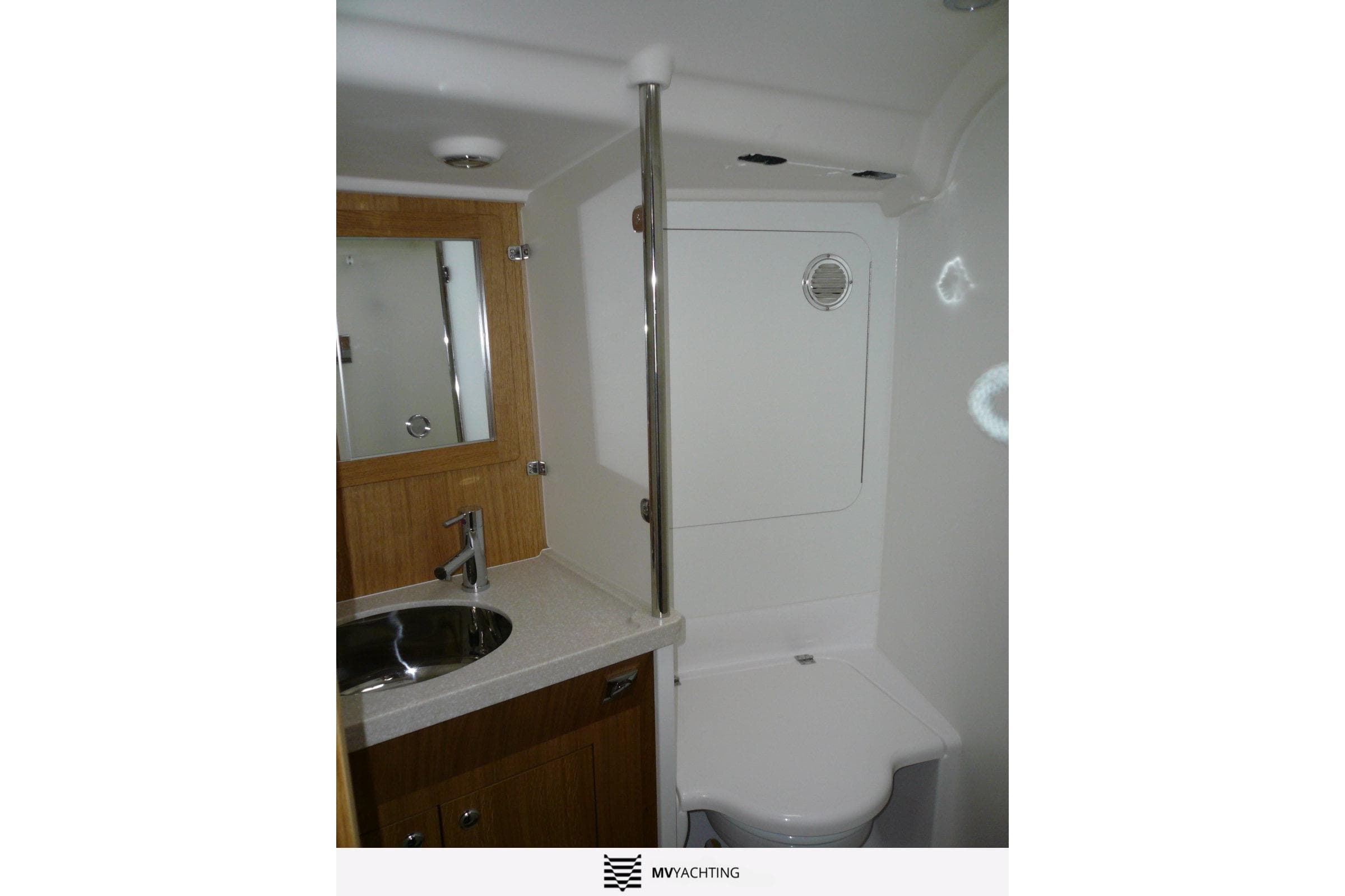 Compact yacht bathroom with sink, mirror, and toilet in a 2010 Maxi 1300 model.