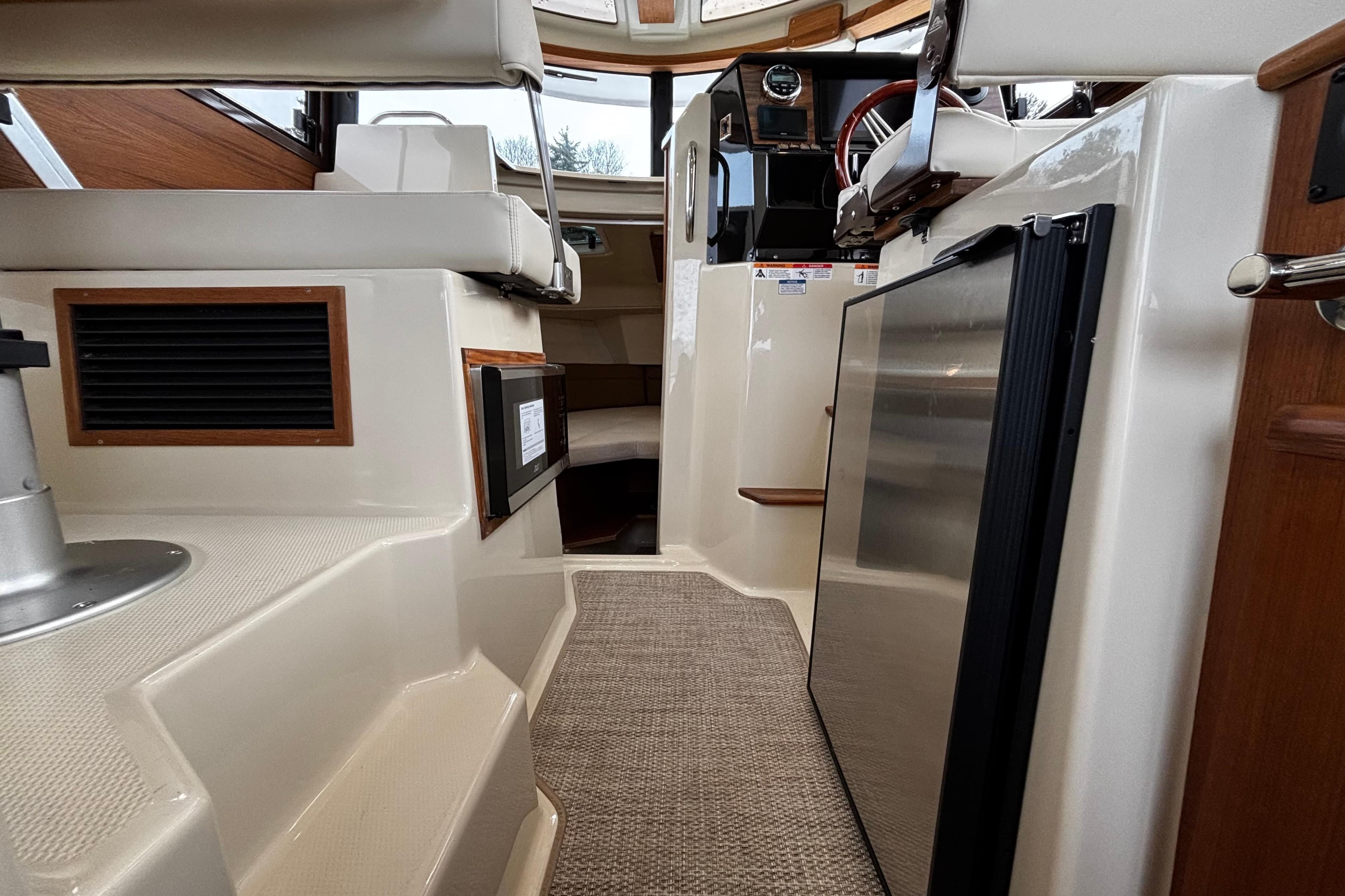 Interior view of 2026 Ranger Tugs R-25 boat, featuring seating and compact kitchen area.