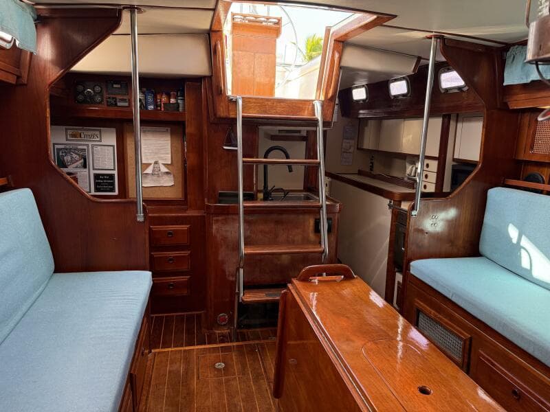 Interior of 1985 Endeavour 42 sailboat with wooden furnishings and blue cushions.