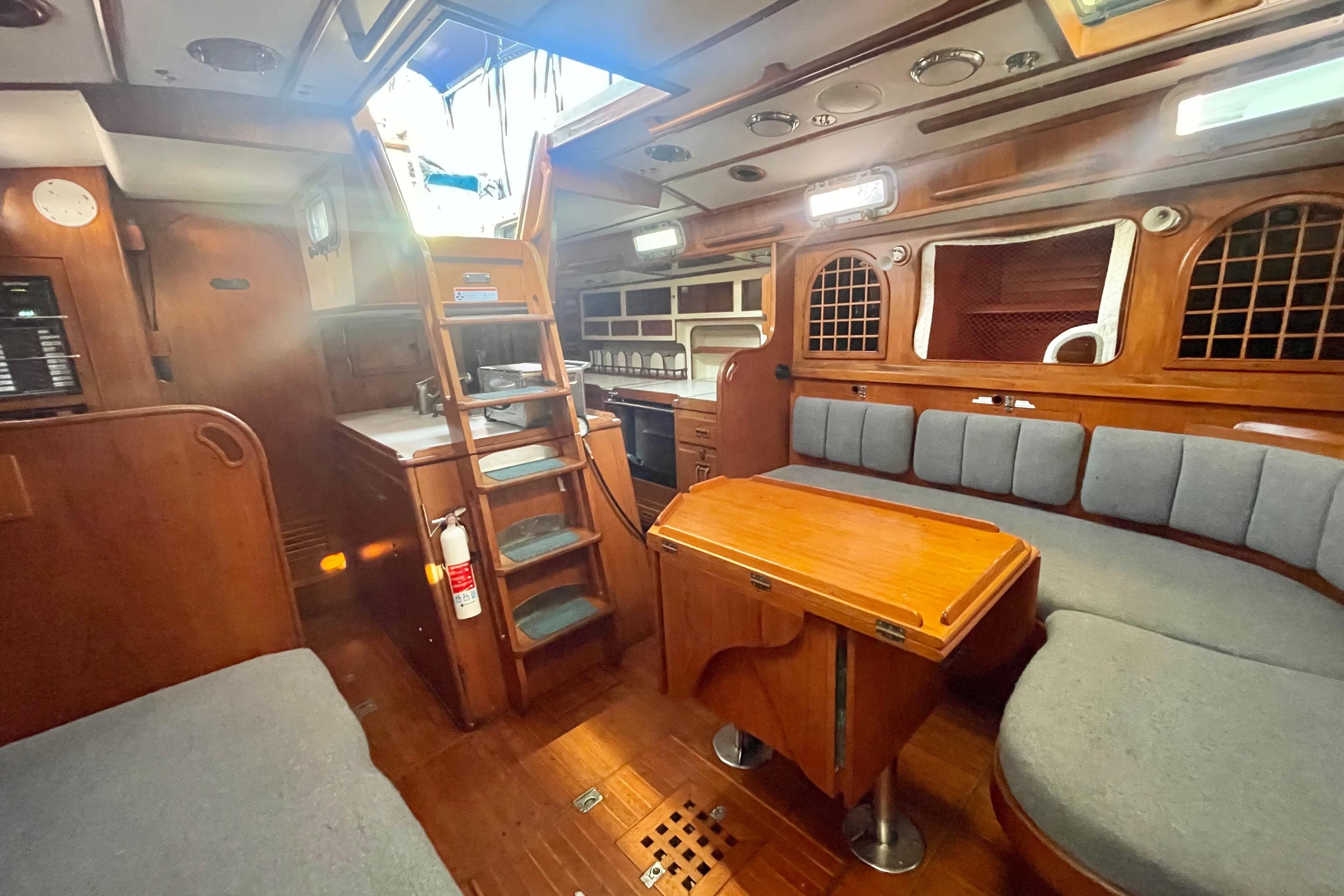 Interior of a 1982 Stevens cutter sailboat with wooden furnishings and seating area.