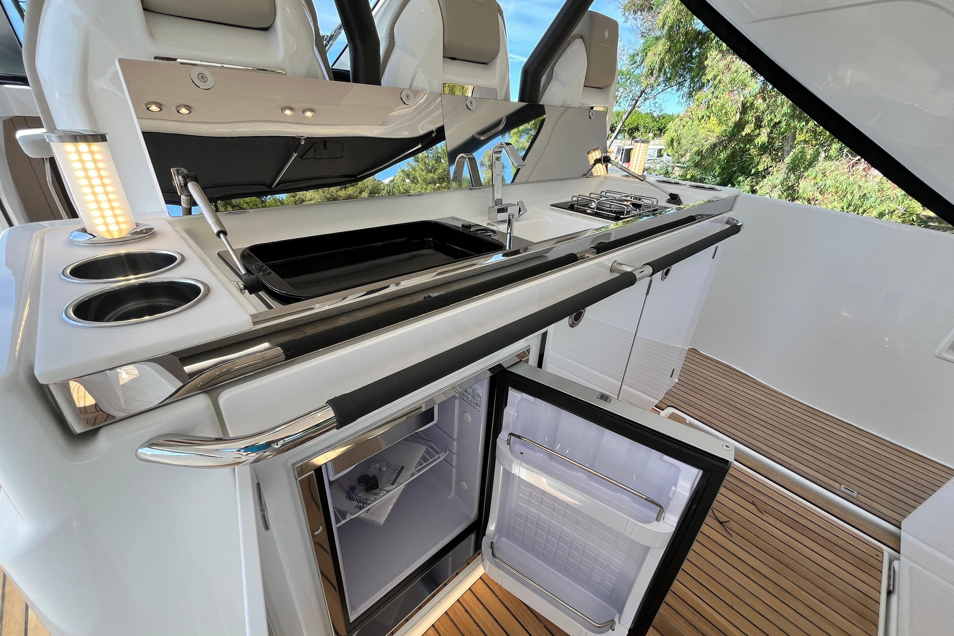 2026 Jeanneau DB/37 IB yacht kitchen with open fridge, sink, and stove.