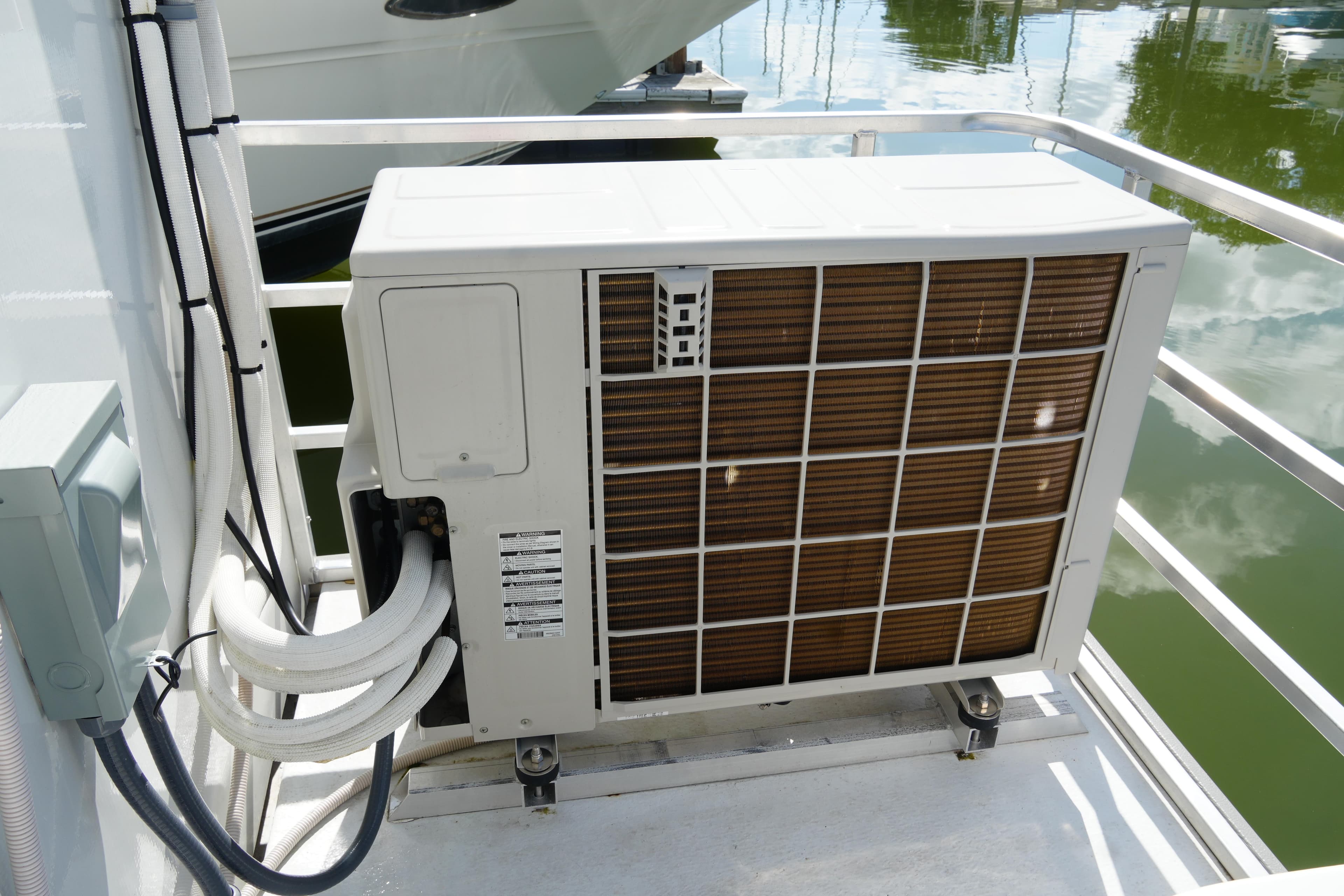 Outdoor air conditioning unit on 2024 Catamaran Aqua Lodge, docked by water.