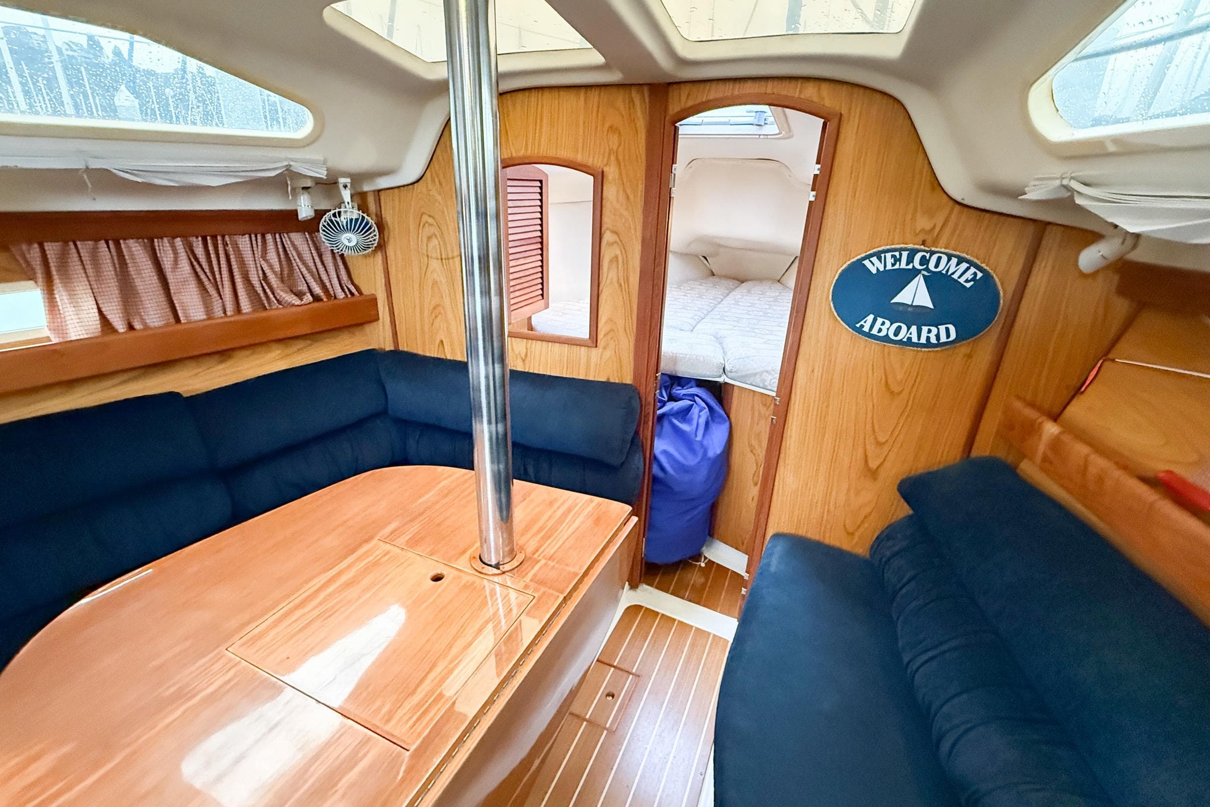 Interior of 2001 Hunter 340 sailboat with cozy seating and "Welcome Aboard" sign.