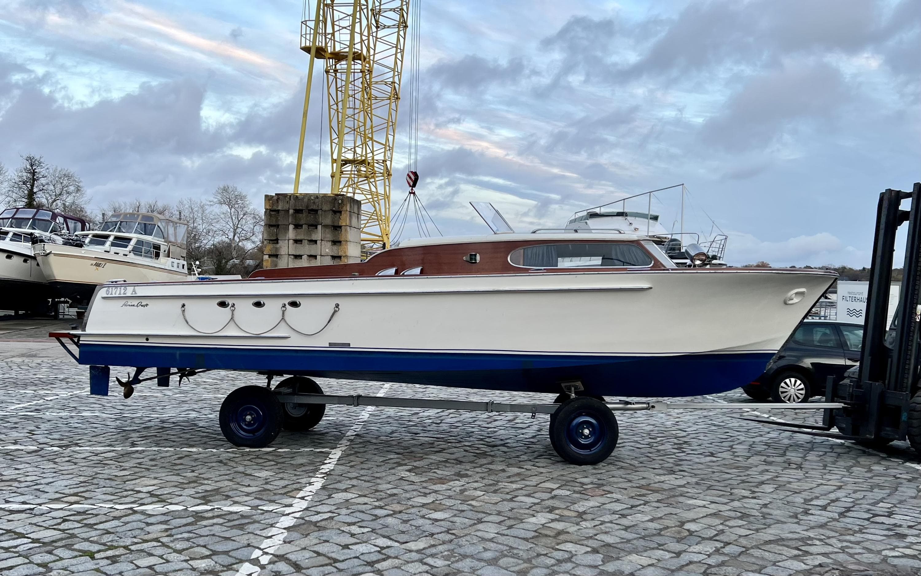 1962 Swiss Craft 820 boat on trailer, dockside, under cloudy sky.