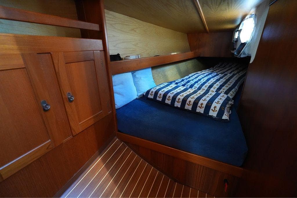 Cozy cabin interior of a 1992 Faurby yacht with wooden furnishings and striped bedding.