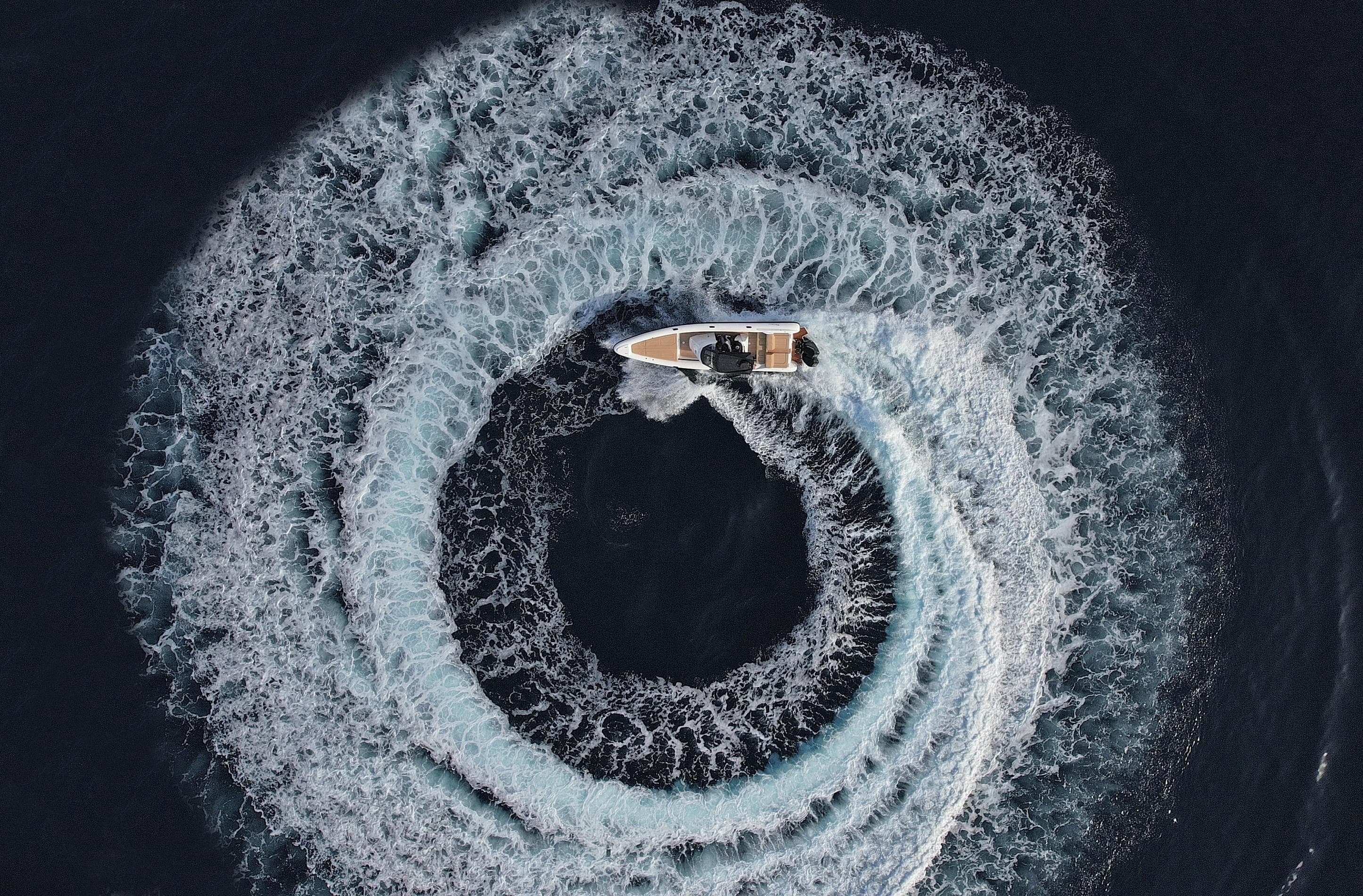 Aerial view of 2024 Ribco Seaferer 36X creating circular wake pattern in dark water.