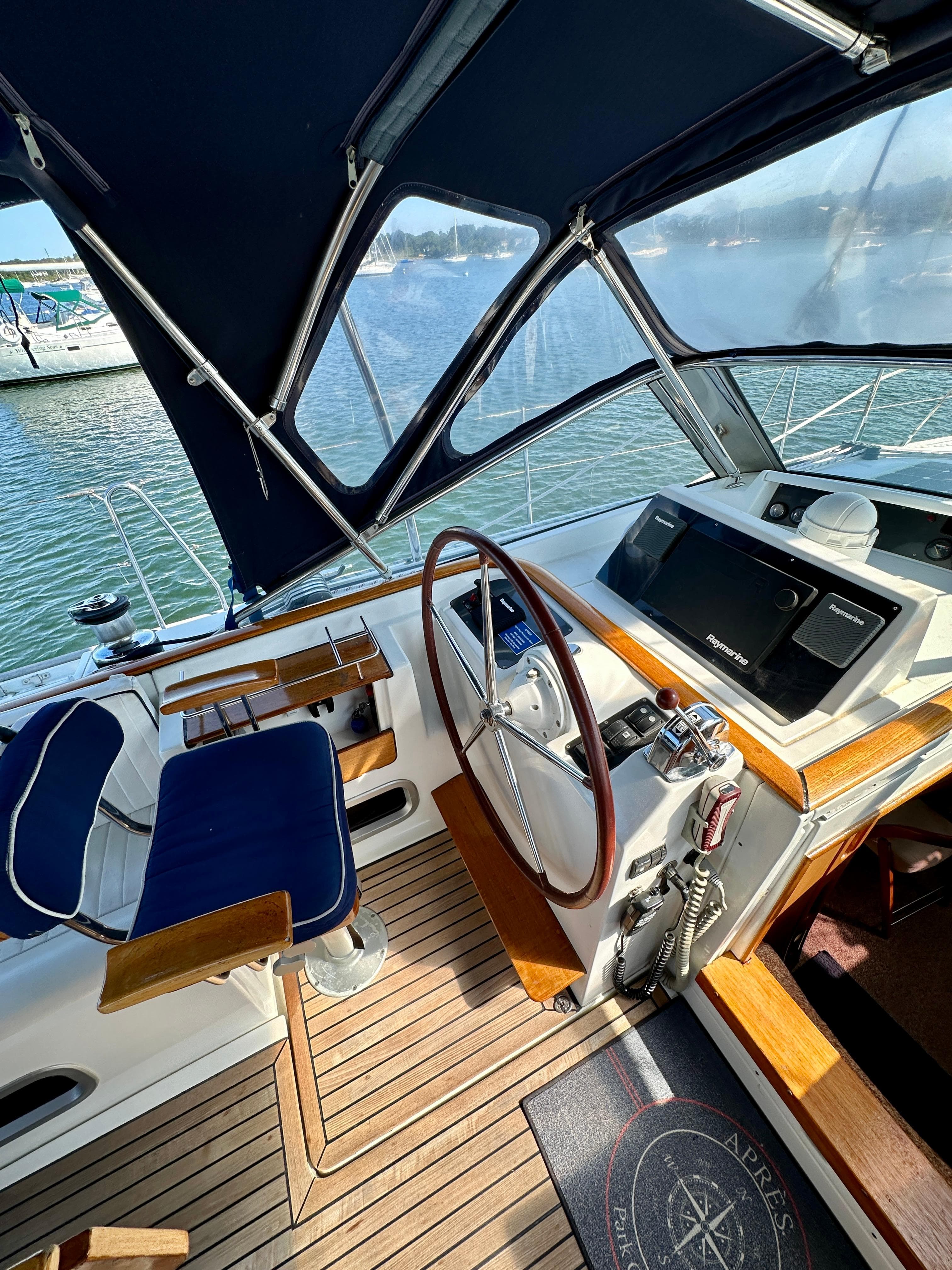 Cockpit of 2010 Beneteau 57 yacht with wooden steering wheel and navigation equipment.