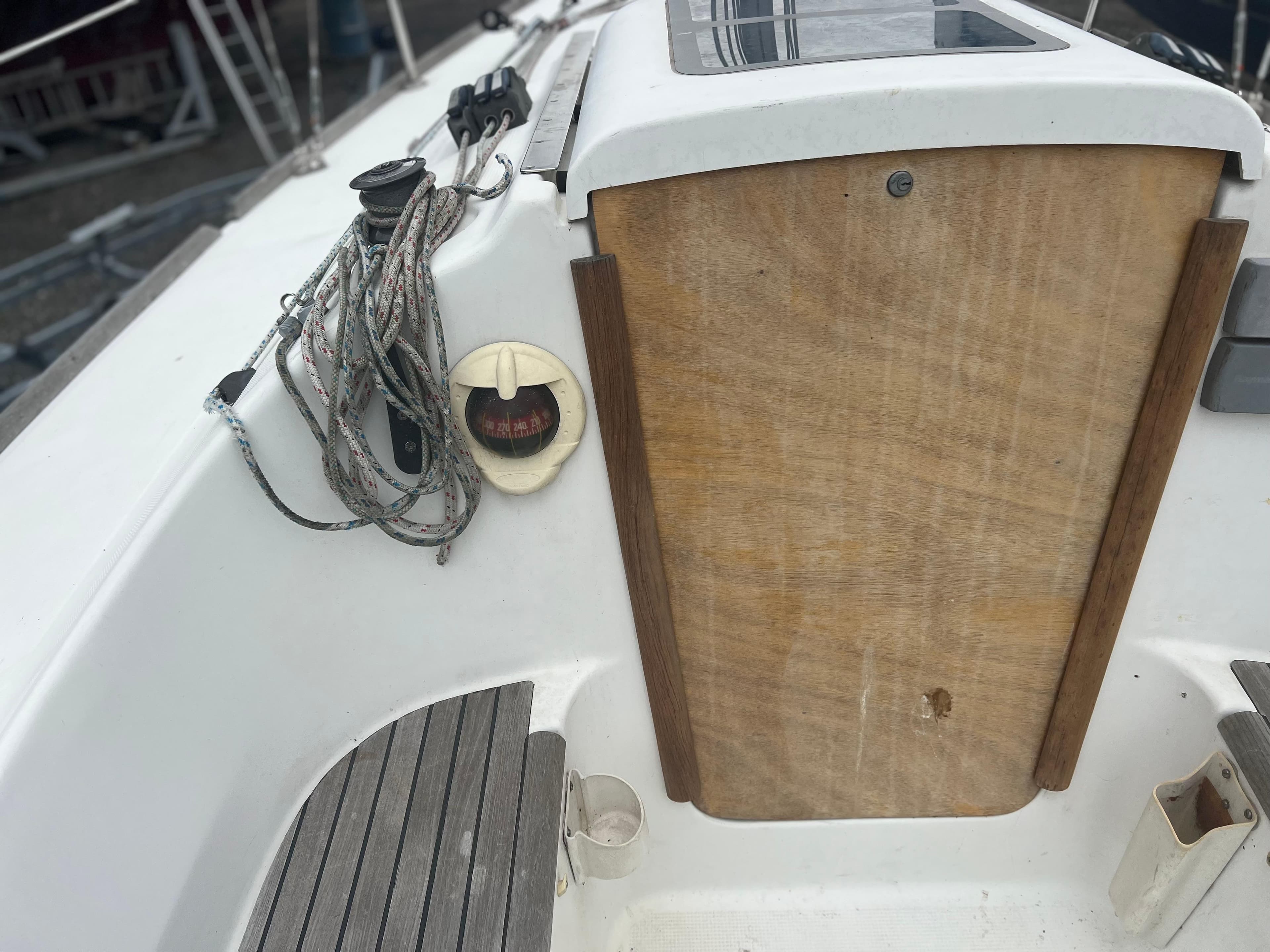 2004 Beneteau First 211 sailboat cockpit with ropes and wooden hatch.
